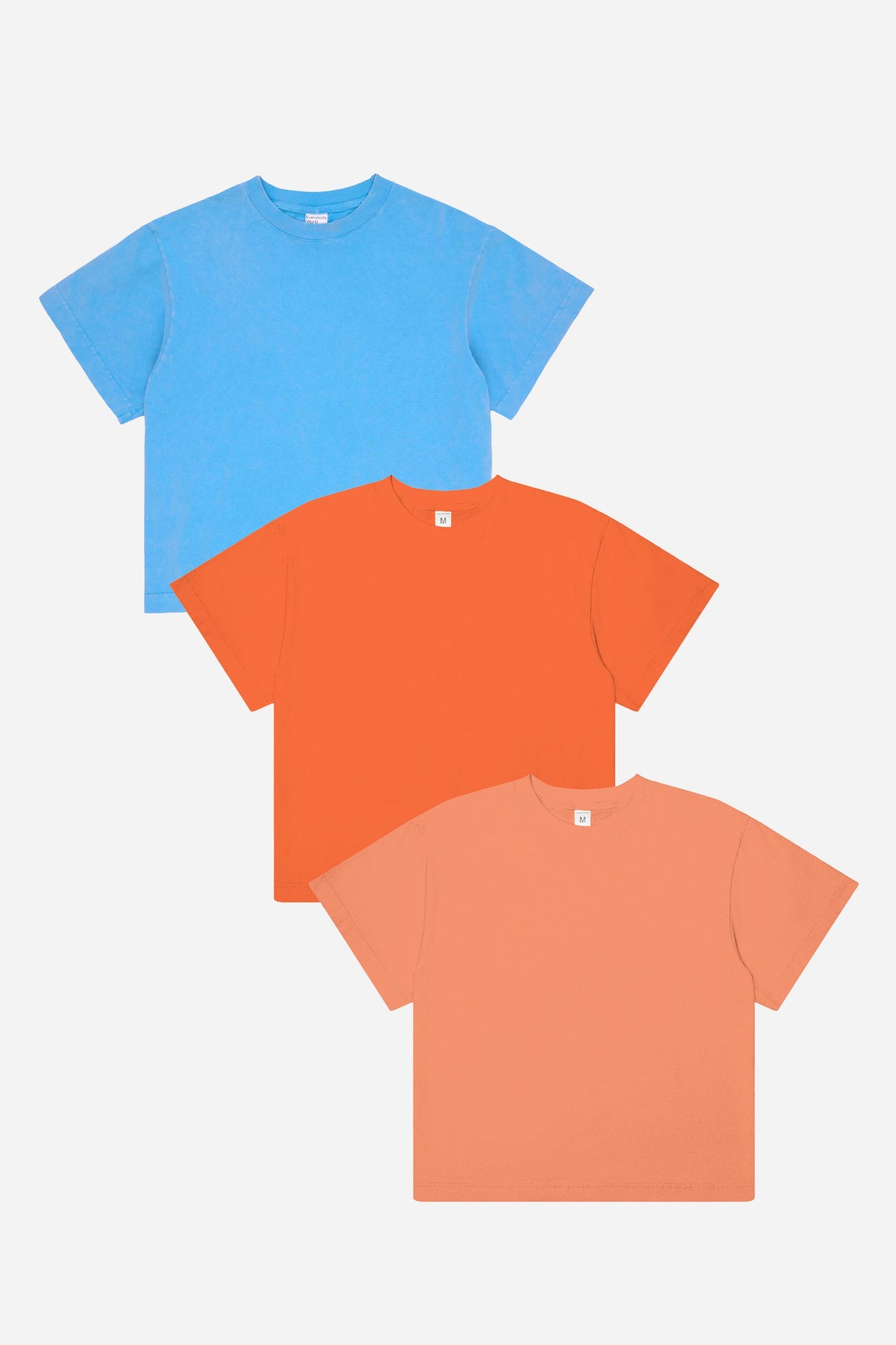 Three t-shirts in blue, orange, and peach on a white background