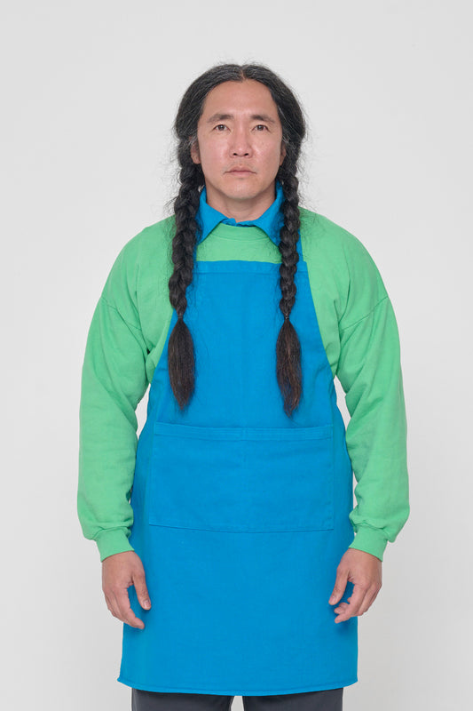 Front view of a person in an Adjustable Apron in Malibu, with straps tied behind their back.