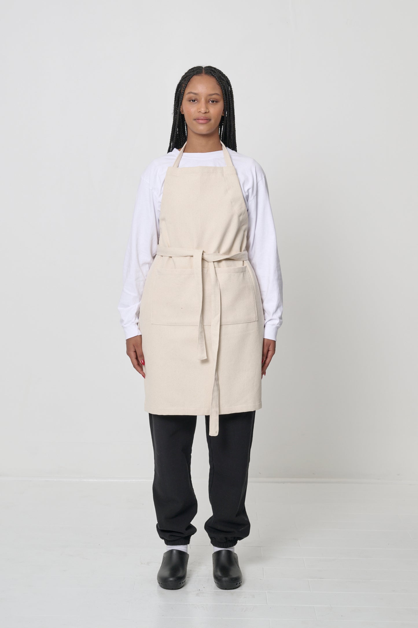 Front view: a person in an Adjustable Apron in Natural, straps tied in the front.