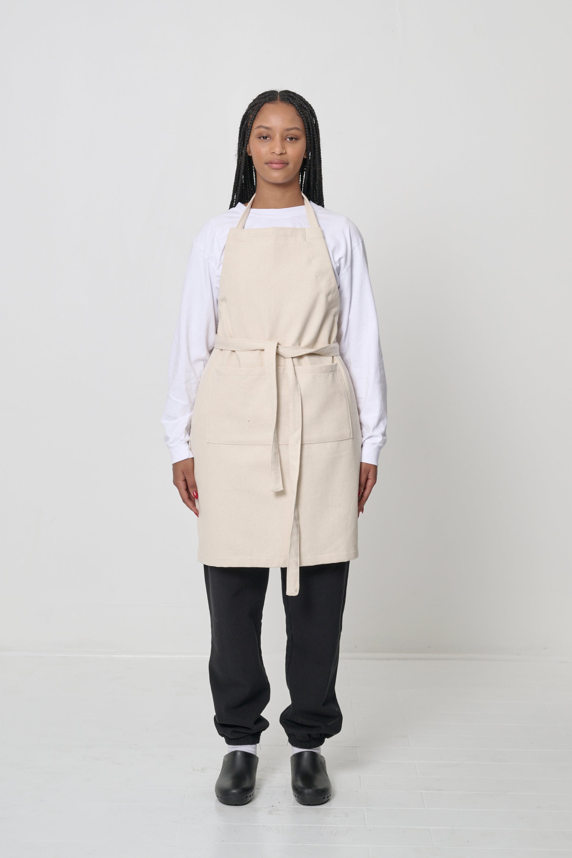 Front view: a person in an Adjustable Apron in Natural, straps tied in the front.