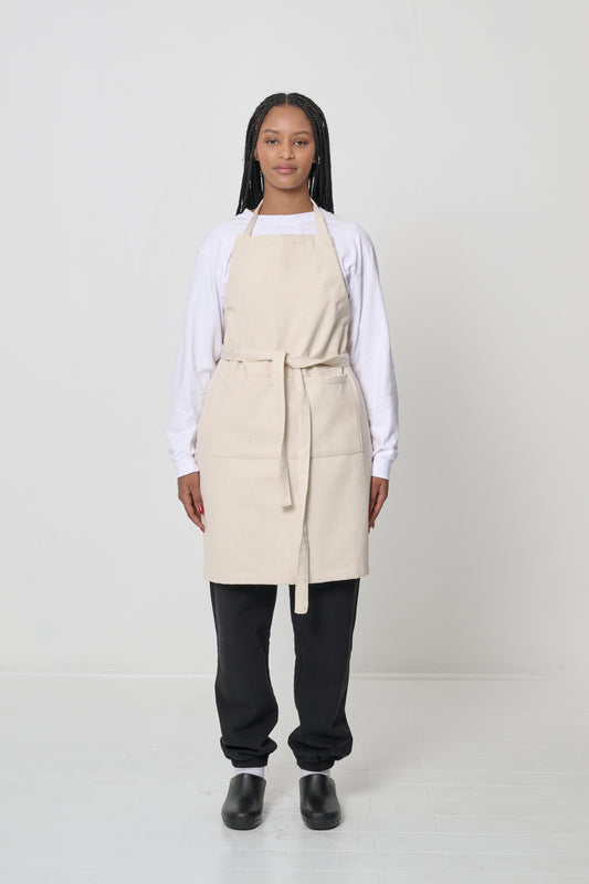 Front view: a person in an Adjustable Apron in Natural, straps tied in the front.