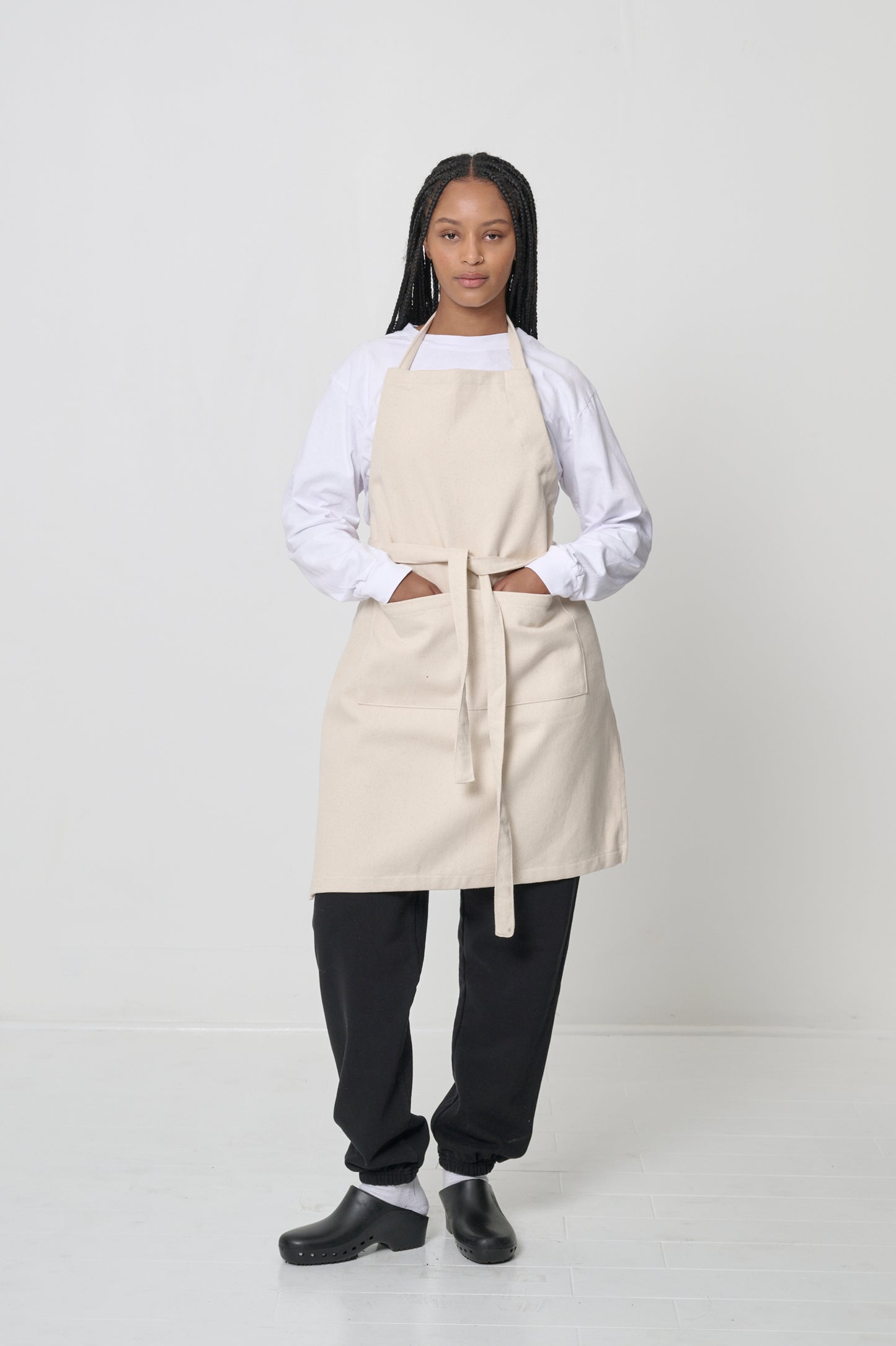 Apron covers the woman's chest to knees, hands in large front pocket.