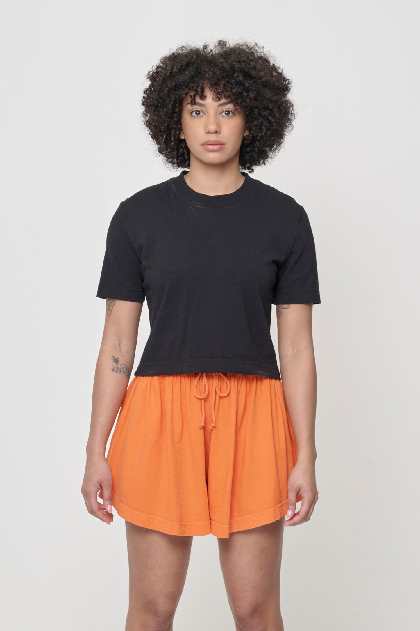 Woman in a cropped black t-shirt and bottom hem hitting bottom of Tubular Shorts waistband.