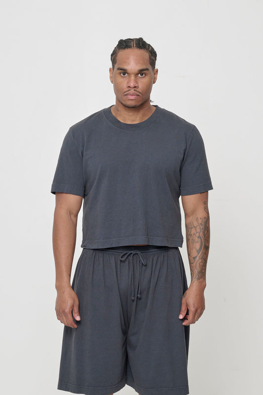 A man wearing dark gray cropped t-shirt with Long Tubular Shorts.