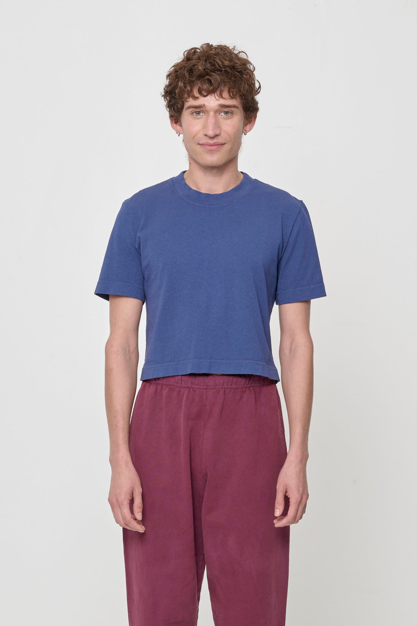 Person wearing dark blue cropped t-shirt and bottom hem hitting top of pants waistband.