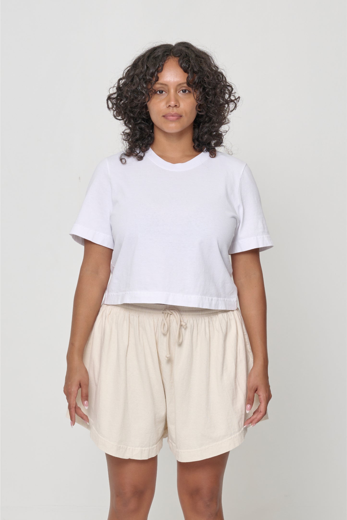 A person wearing cropped t-shirt and bottom hem hitting middle of shorts waistband.