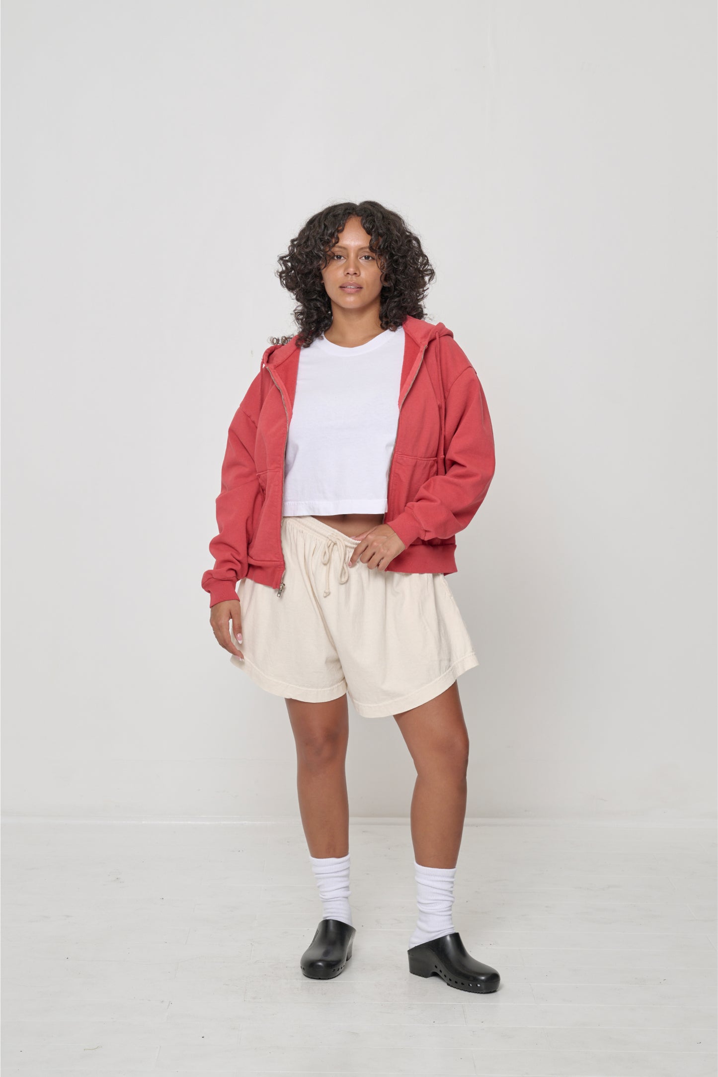 A woman wearing navel-baring t-shirt with Tubular Shorts and Trash Zip Up Hoodie.