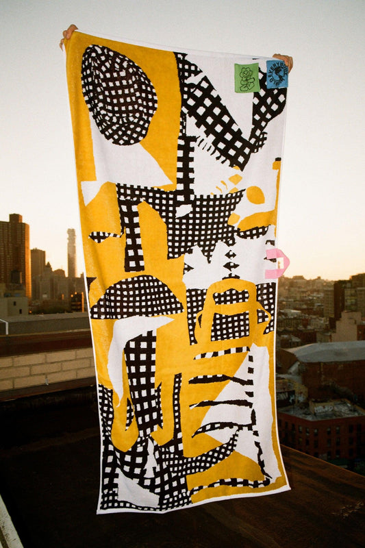 Person holding up a yellow, black, and white abstract patterned towel to display its full design.