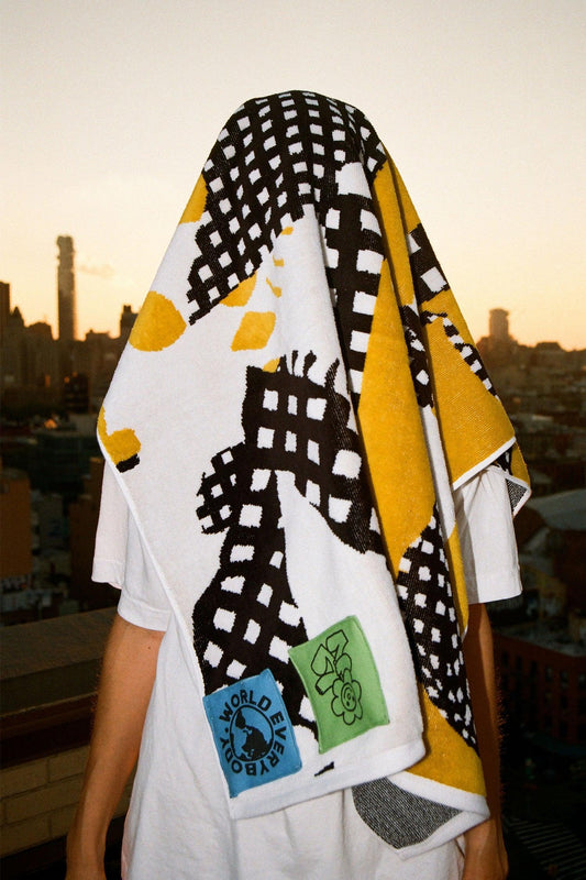 Towel draped over a person's head, standing with a city skyline in the background