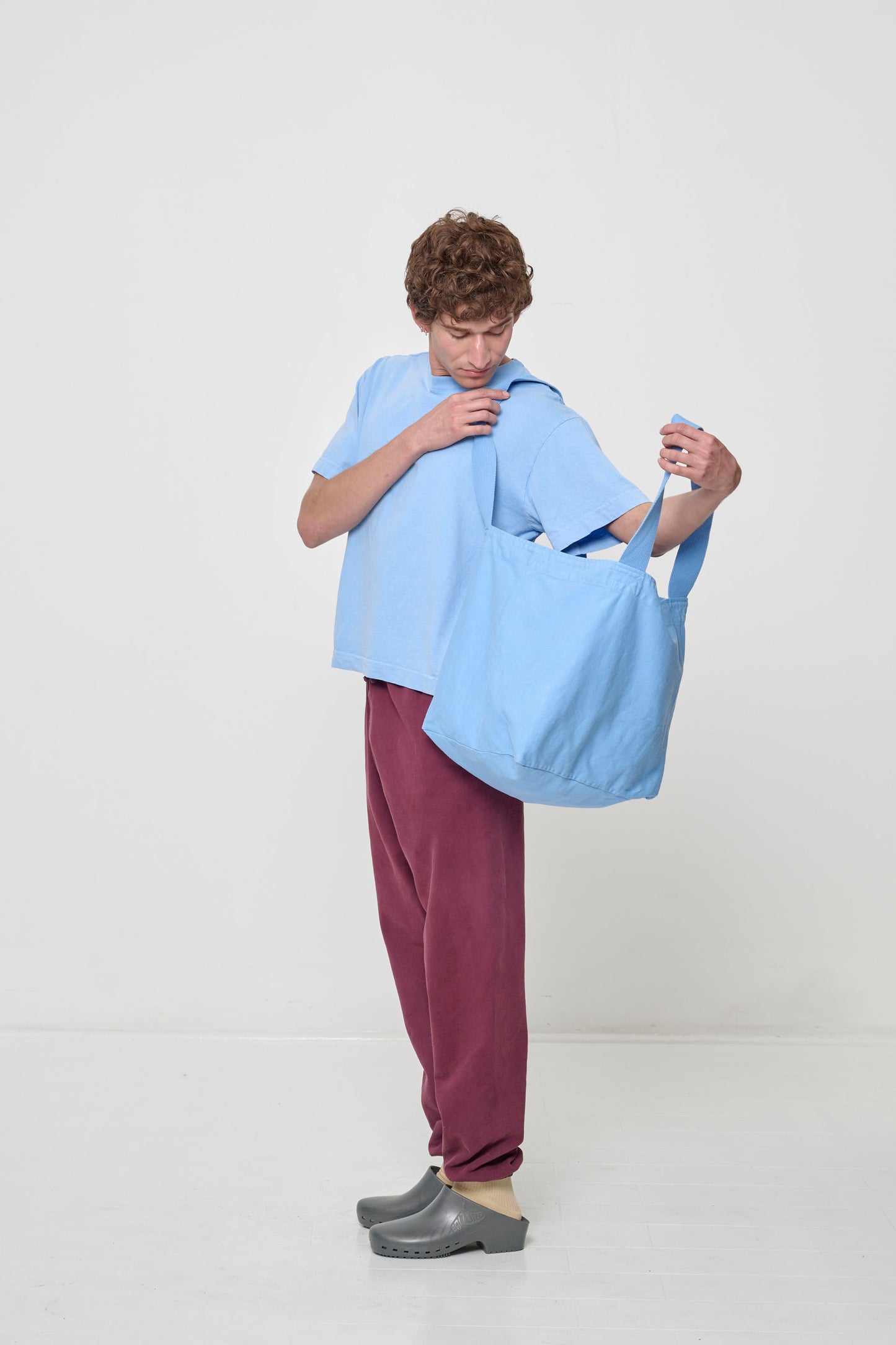 Person holding Big Tote in Cielo light blue open on their shoulder, showing how wide the bag opens with the deep bottom panel.