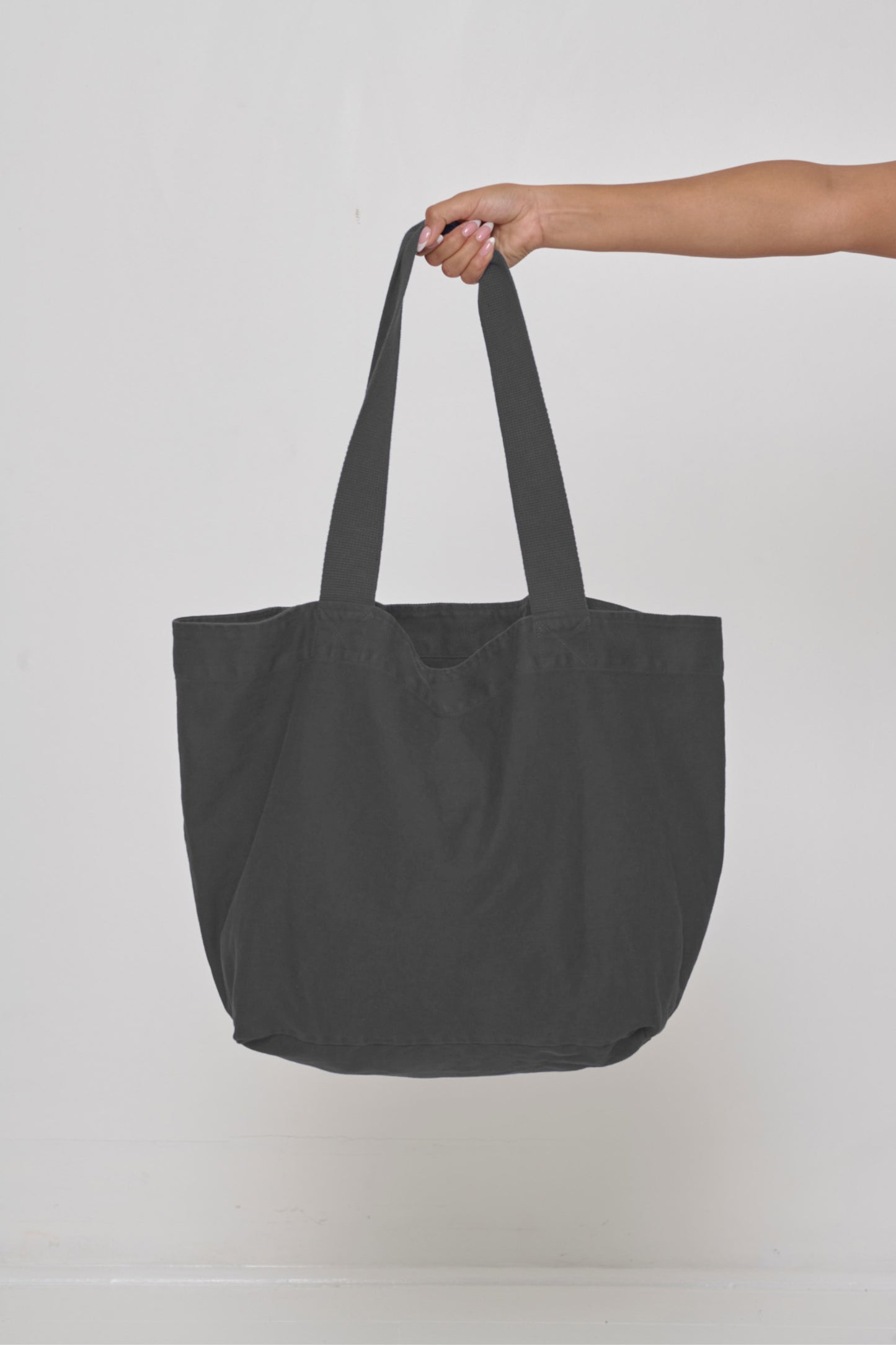 Big Tote in Slate dark gray, held in a person's hand, showing gussets, depth, stitching, and web straps.
