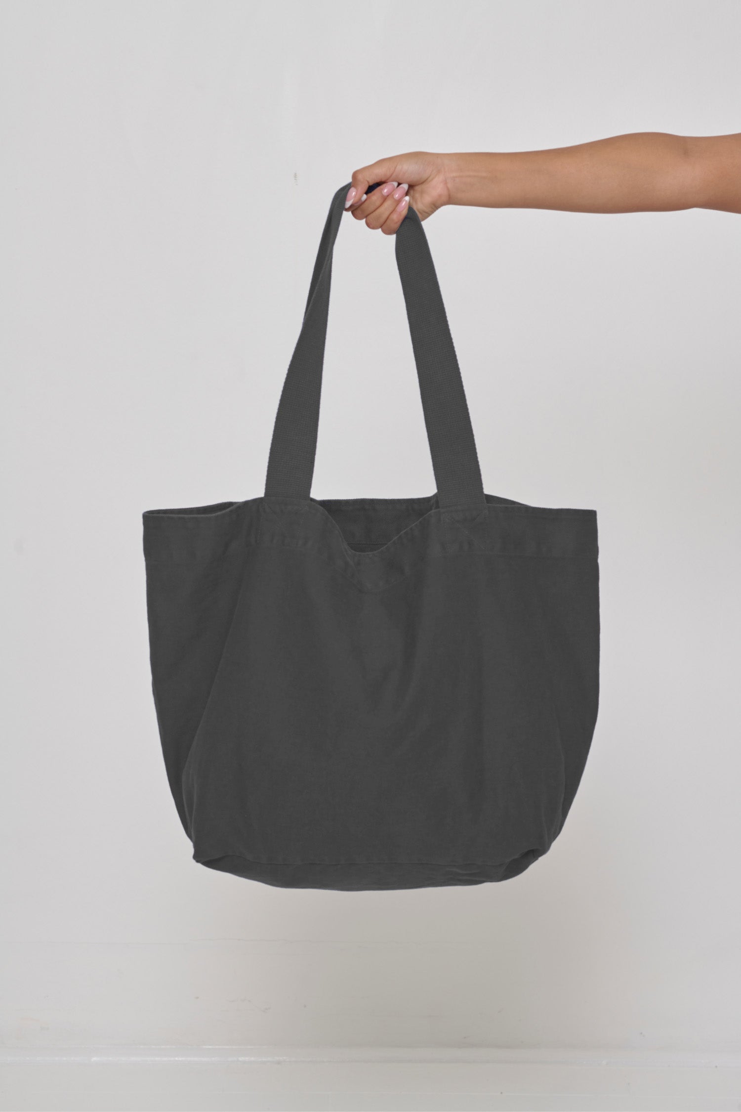 Big Tote in Slate dark gray, held in a person's hand, showing gussets, depth, stitching, and web straps.