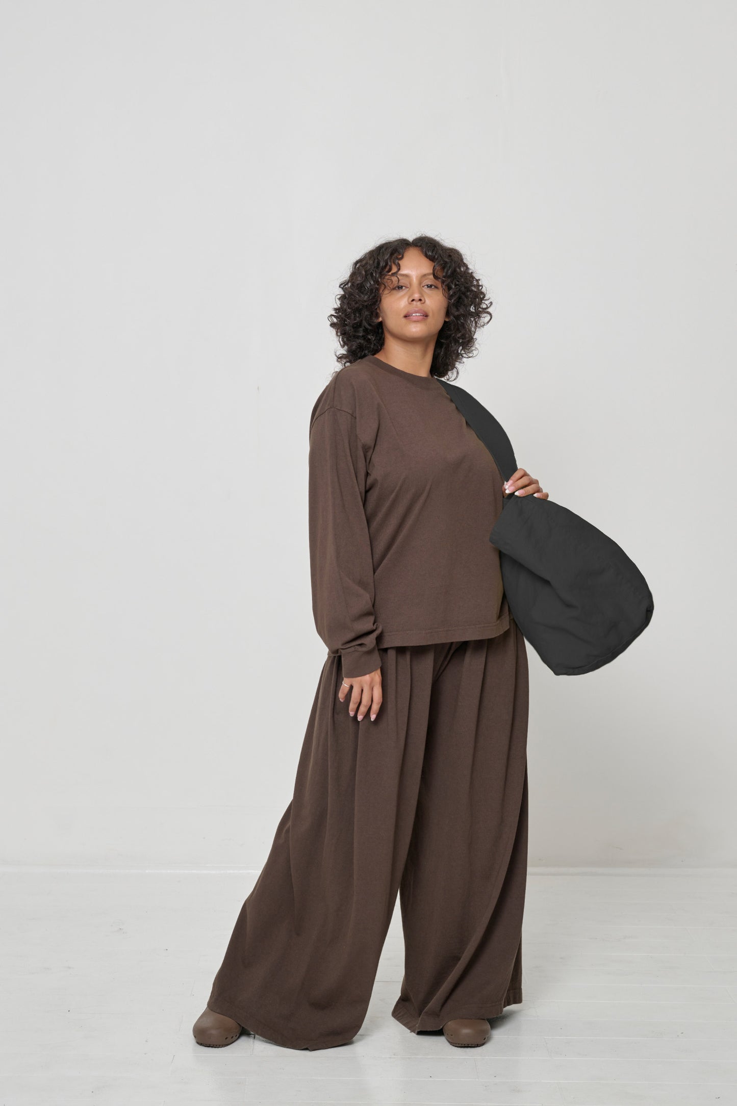 Woman holding it over her shoulder, showing that the bag opening begins at her mid-torso.