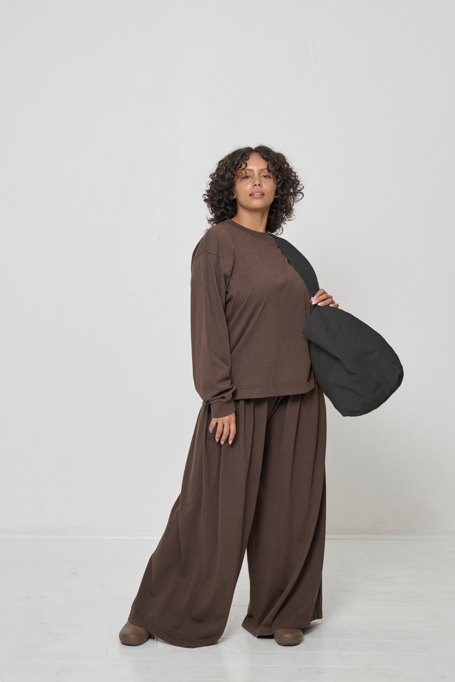 Woman holding it over her shoulder, showing that the bag opening begins at her mid-torso.