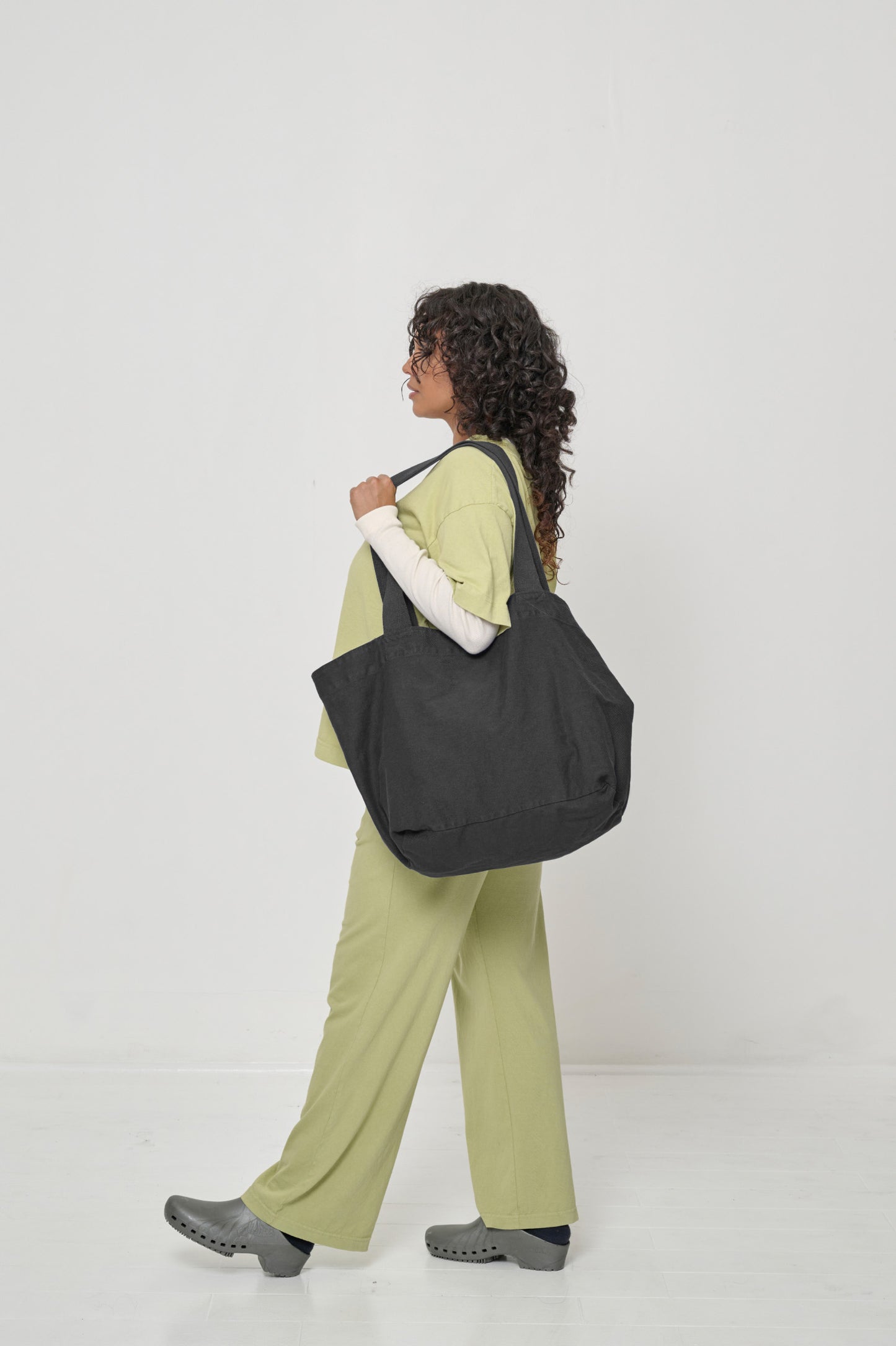 Woman carrying it over her shoulder, showing fabric folds and the flexibility of the bag.