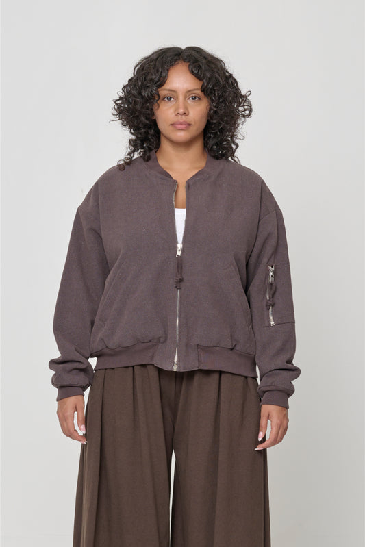 Person wearing the Biodegradable Bomber Jacket in Soil, a heather medium brown color.
