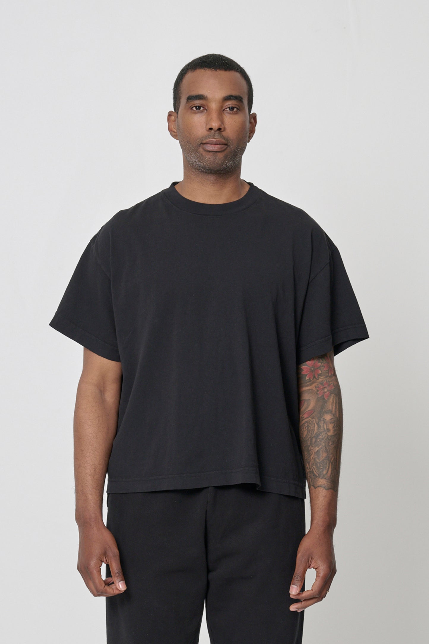 A 6'2" man in a size L Black Boxier Trash Tee. Bottom hem at the middle hip.