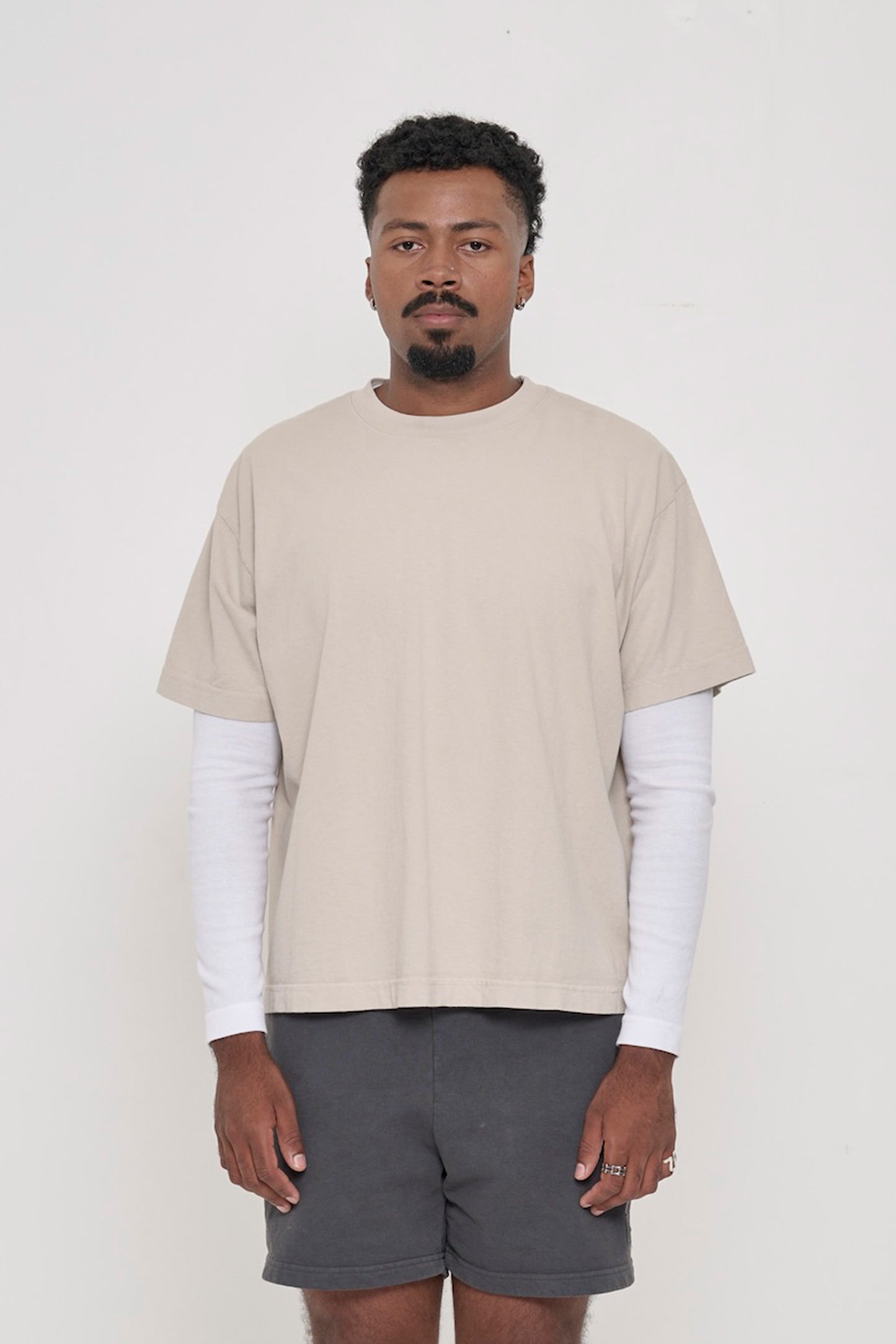 A 6'2" man in a size L Oat beige Boxier Trash Tee. Bottom hem at the lower middle hip.