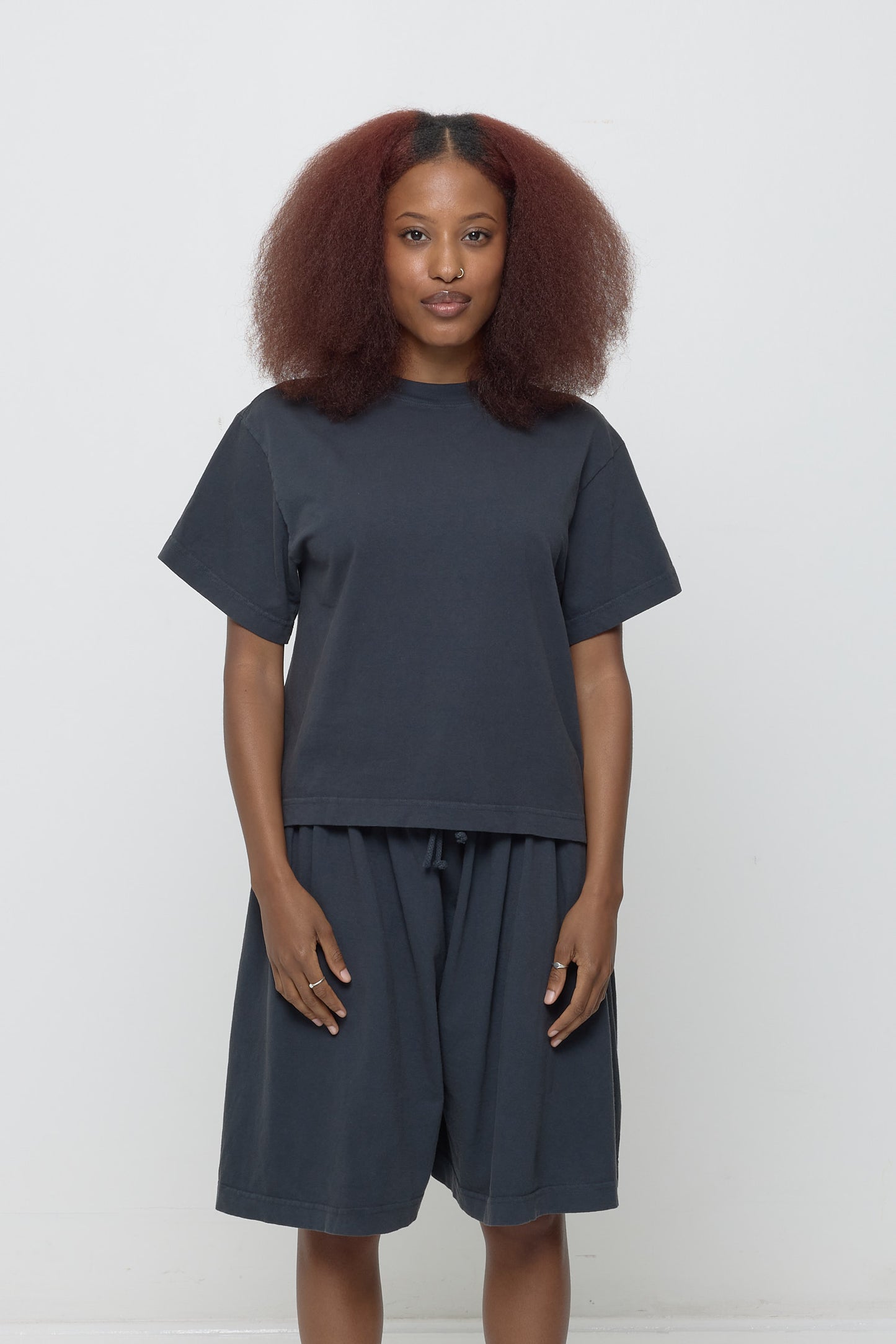 A 5'3" woman in a dark gray Boxier Trash Tee in size XS. Bottom hem at the hip.