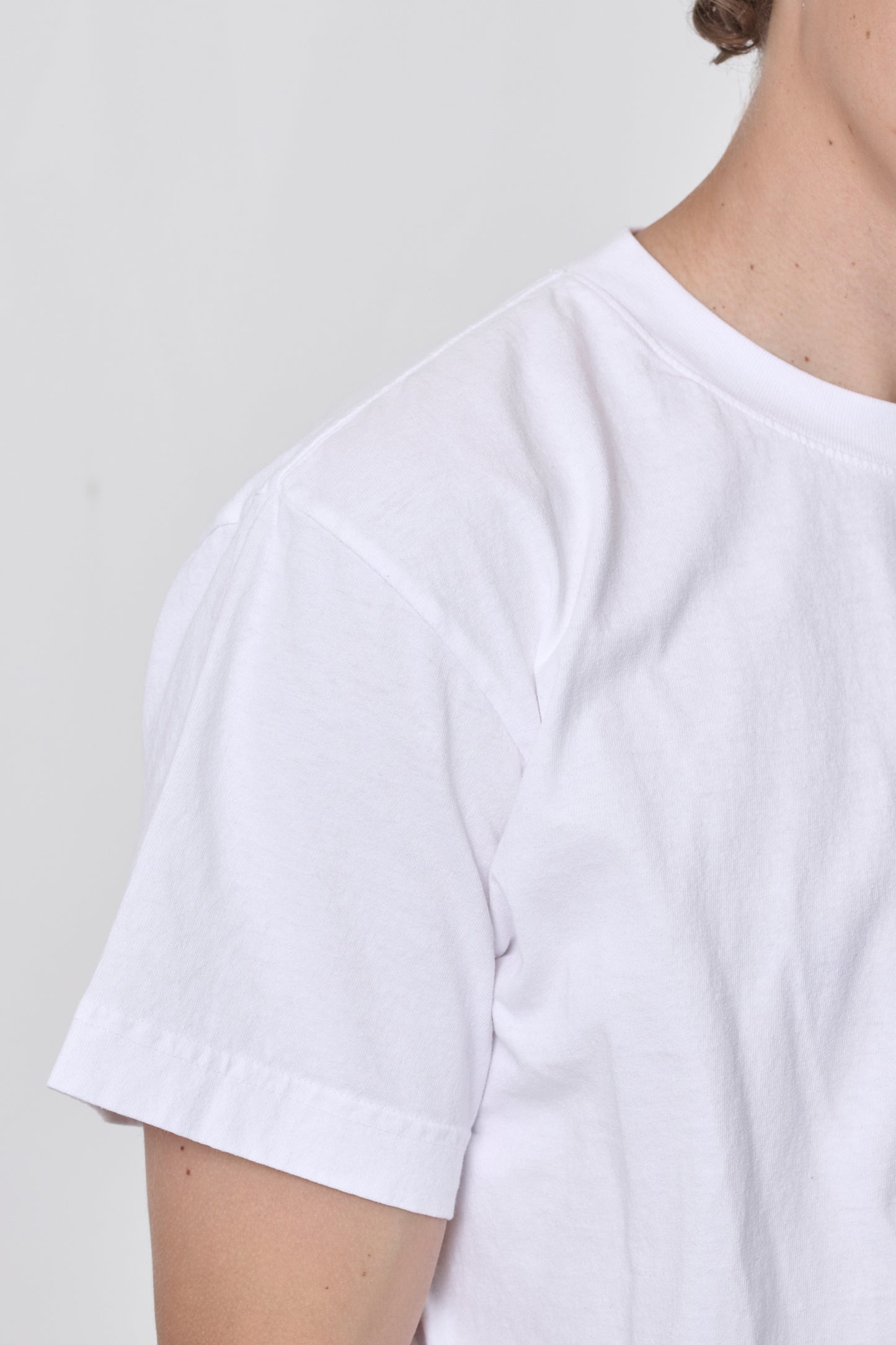 Detail of sleeve and neckline stitching as shown on a man wearing White Boxier Trash Tee.