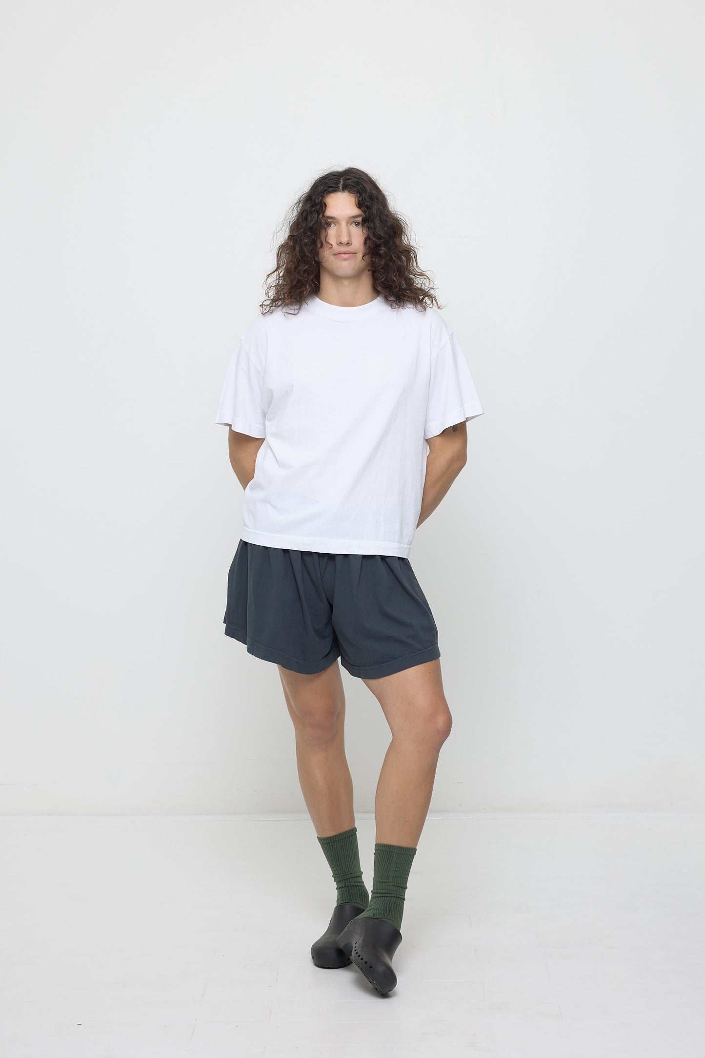 A person wearing a White Boxier Trash Tee with Slate Tubular Shorts and Calzuro clogs.