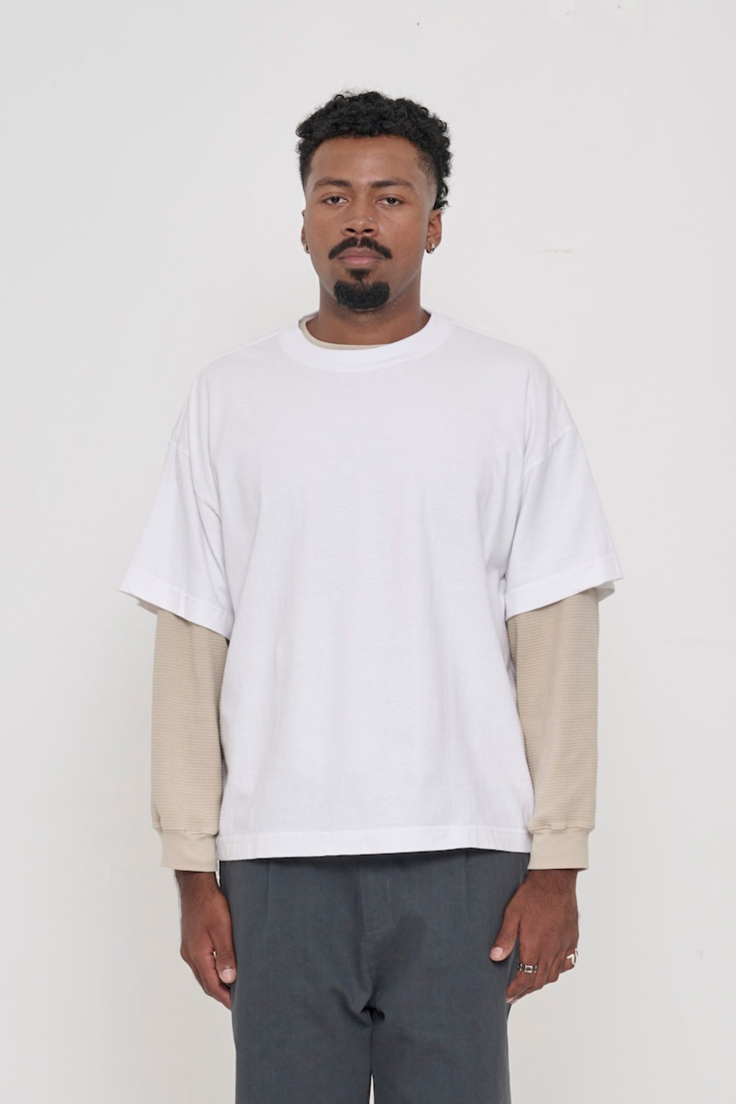 Front view of a 6'2" man wearing a White Boxier Trash Tee in size XL, layered over an Oat thermal. Hem at lower hip.