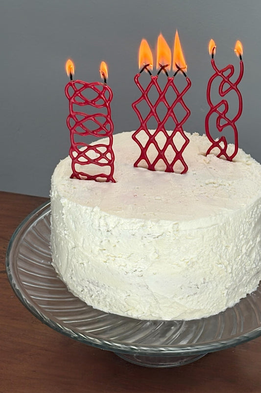 White cake with red braided candles on a gray background
