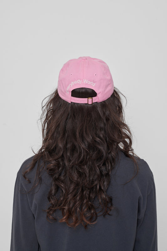 Back view on a woman: 'Everybody,World' embroidered in an arc above the adjustable closure.