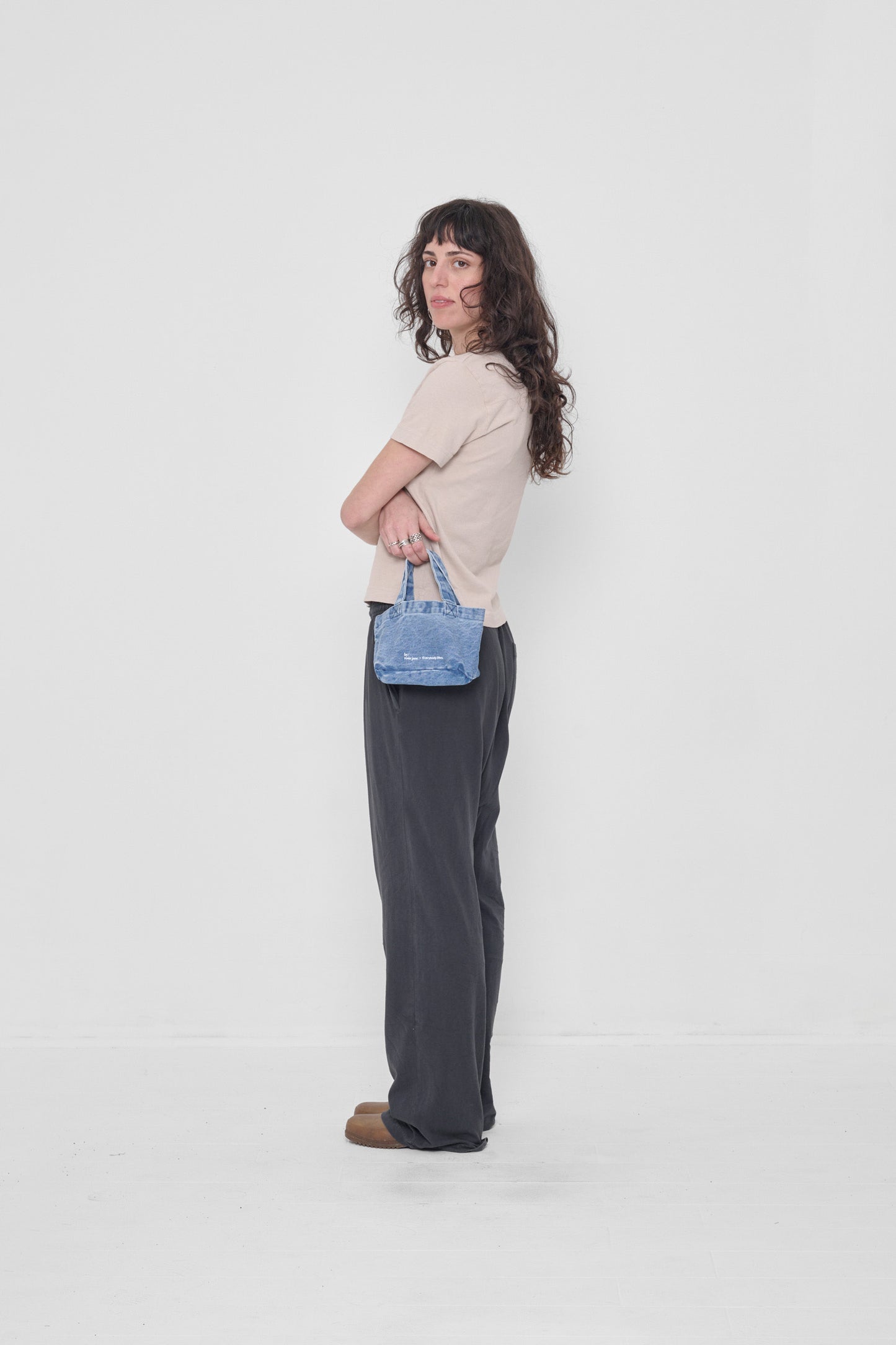 Woman holding Denim Mini Tote to her side showing its size.