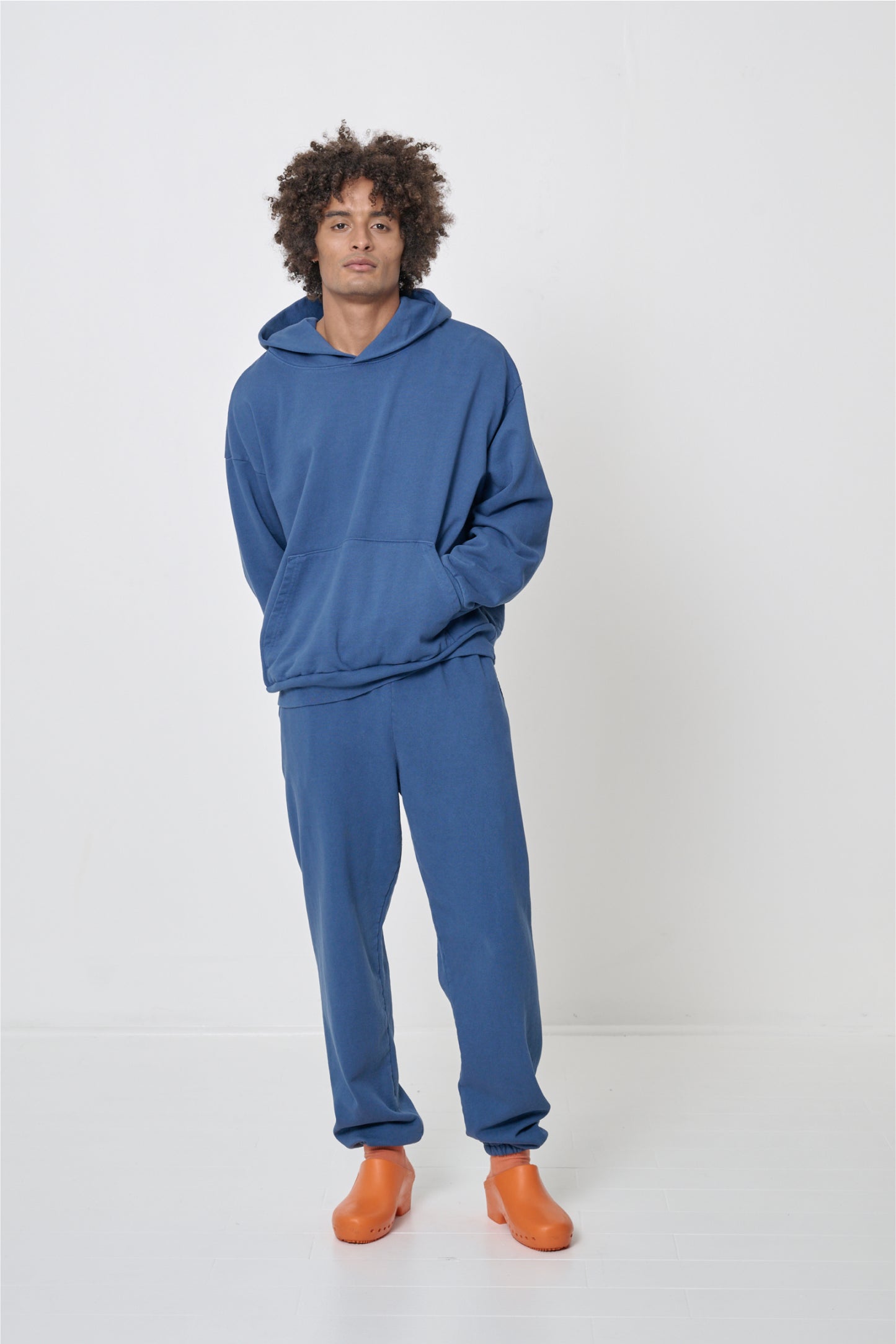 Man wearing a matching dark blue hoodie and sweatpants set with Orange Calzuro Classic Clogs.