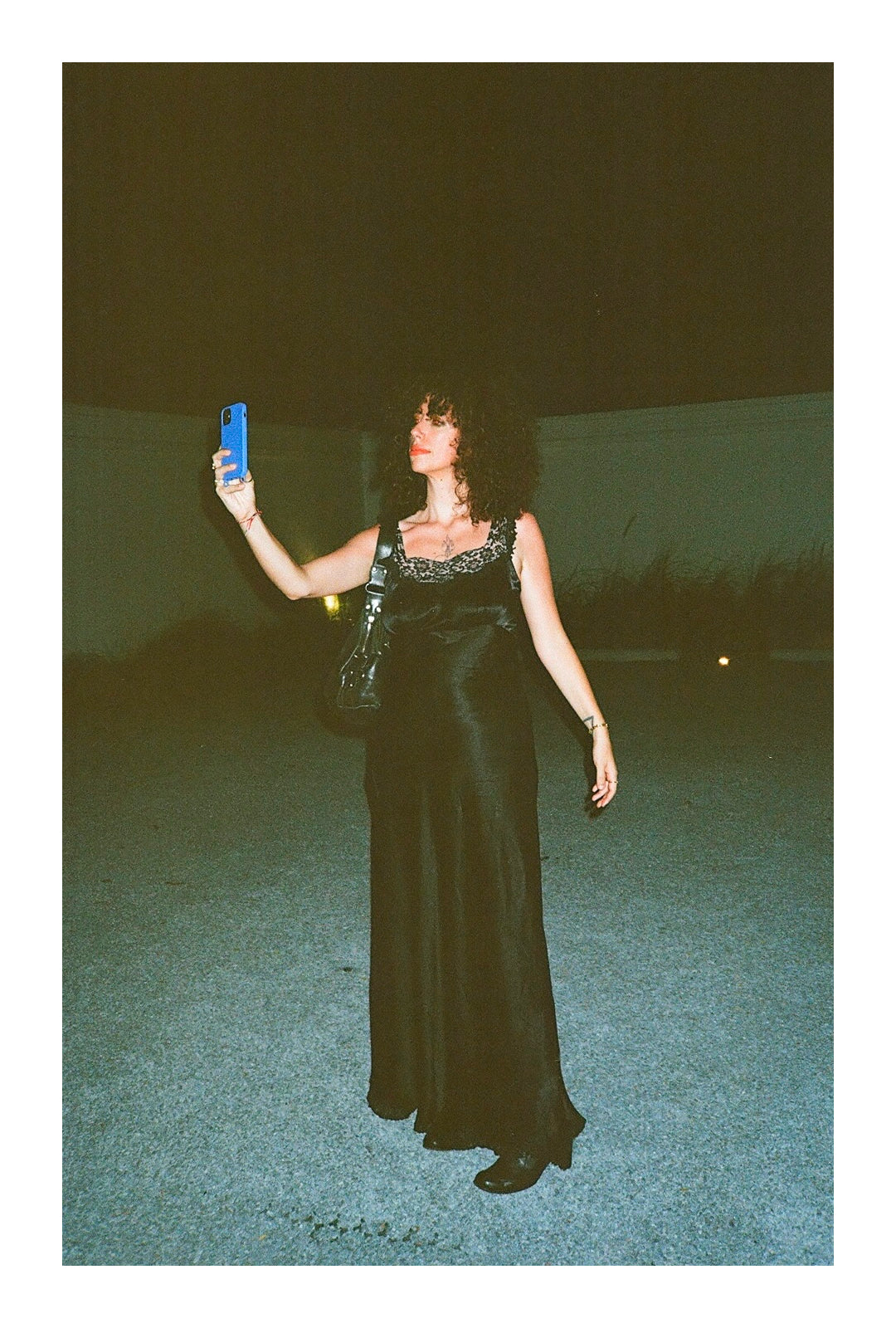 Jerico in a sleeveless black gown, holding up a phone to take a selfie.