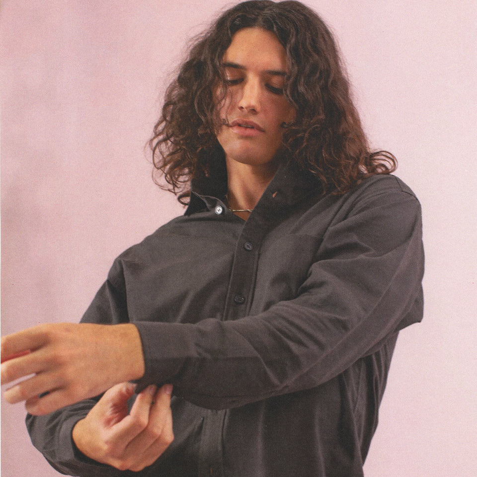 Person buttons the cuff of a Peach Fuzz Cotton Twill Button-Up Shirt in Slate.