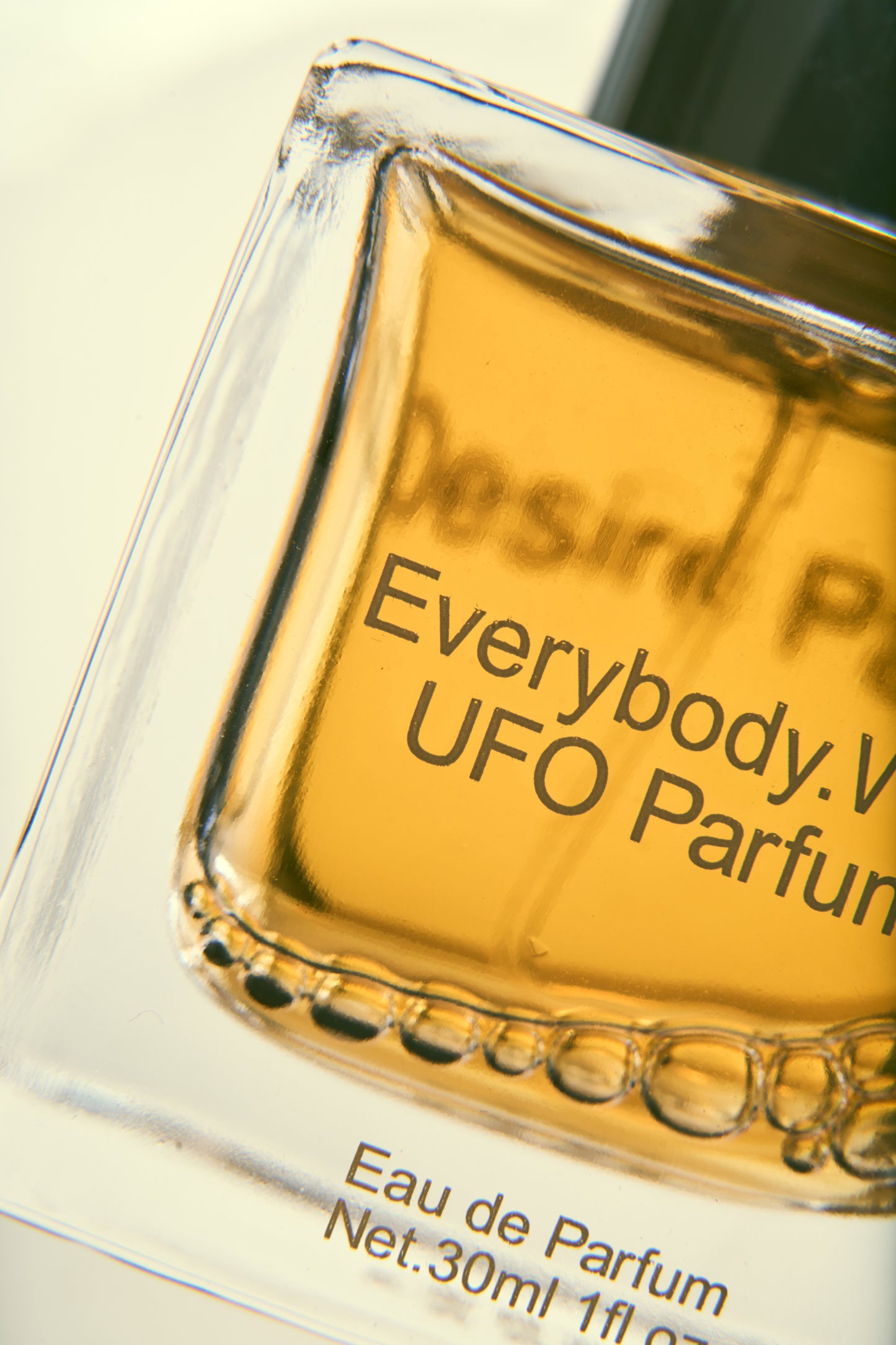 Close up of glass bottle printed with text "Everybody.World UFO Parfum" and volume info.