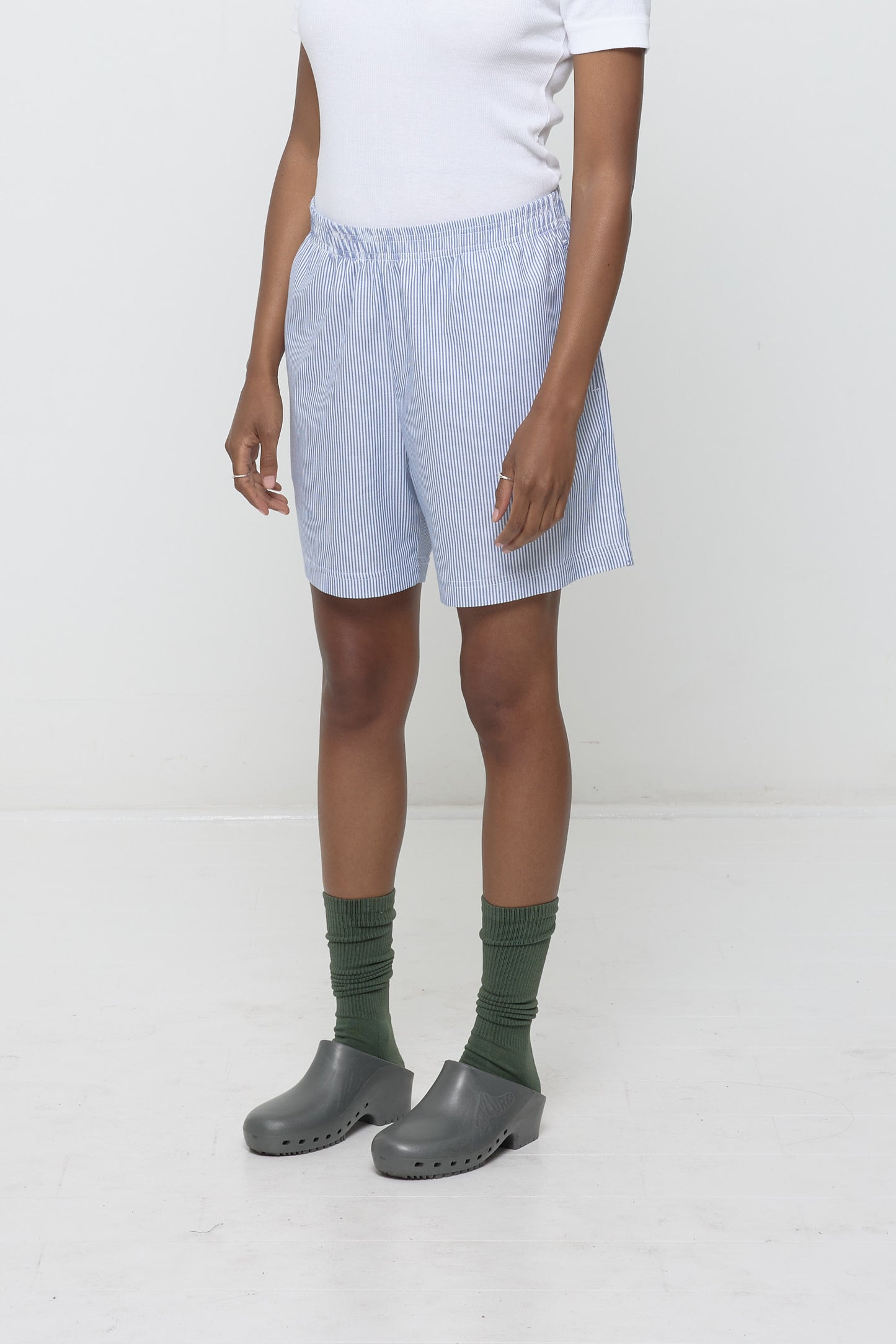 Close-up 3/4 view of Stripe Poplin Everyday Shorts on model. Highlights elastic waist and skinny blue and white stripes.