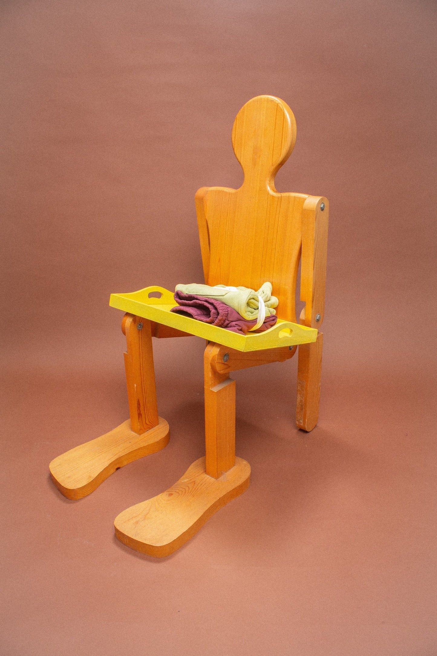 Wooden mannequin chair with Cardamom light green and Burgundy shorts folded on its lap.