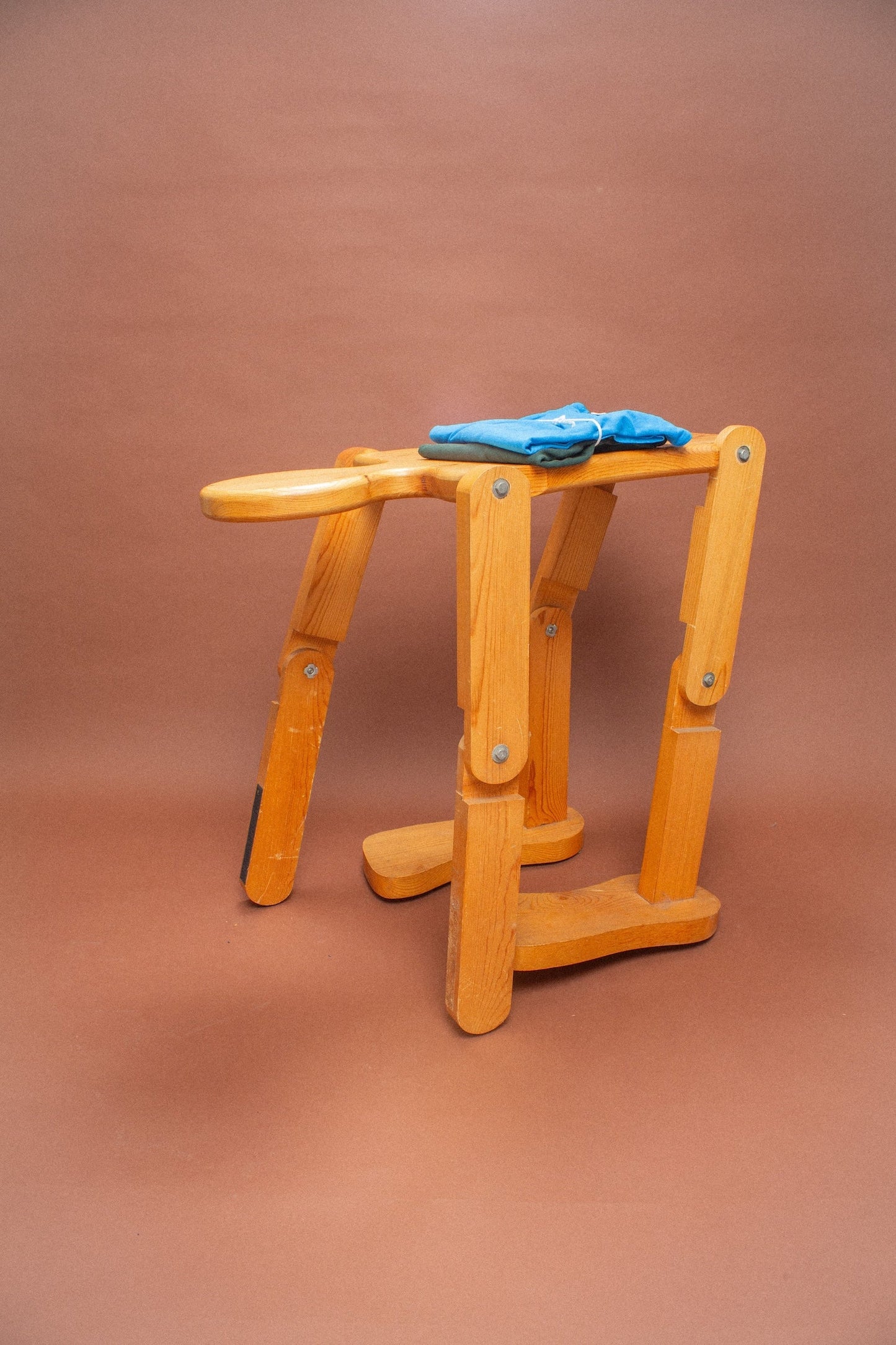 Wooden stool with blue and green folded tees on it.