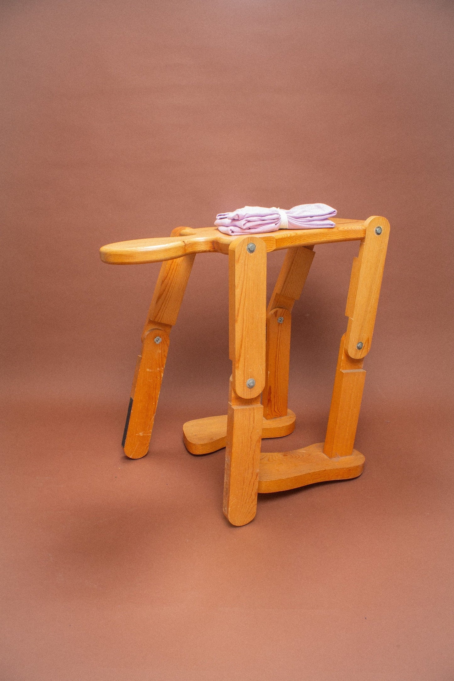 Wooden stool with 2 folded lavender tees on it.