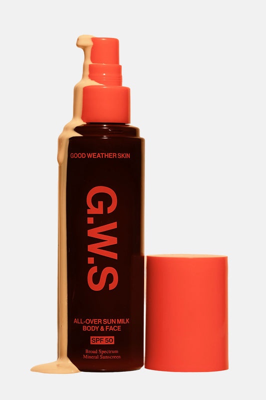 Orange bottle packaging of Good Weather Skin All-Over Sun Milk, with the cap off and liquid solution.