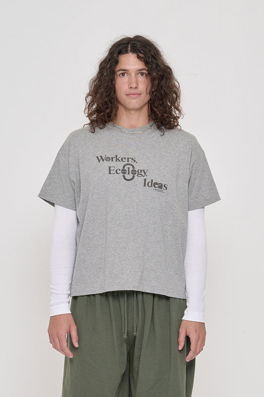 Person in Heather Boxier Tee. 'Workers, Ecology, Ideas' screenprinted on the front.