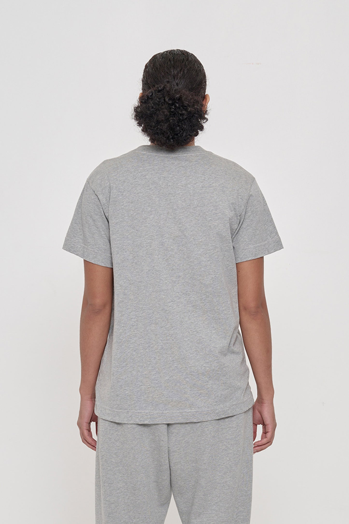 Back view of a woman in a Heather Short Sleeve Tee showing the relaxed fit throughout.