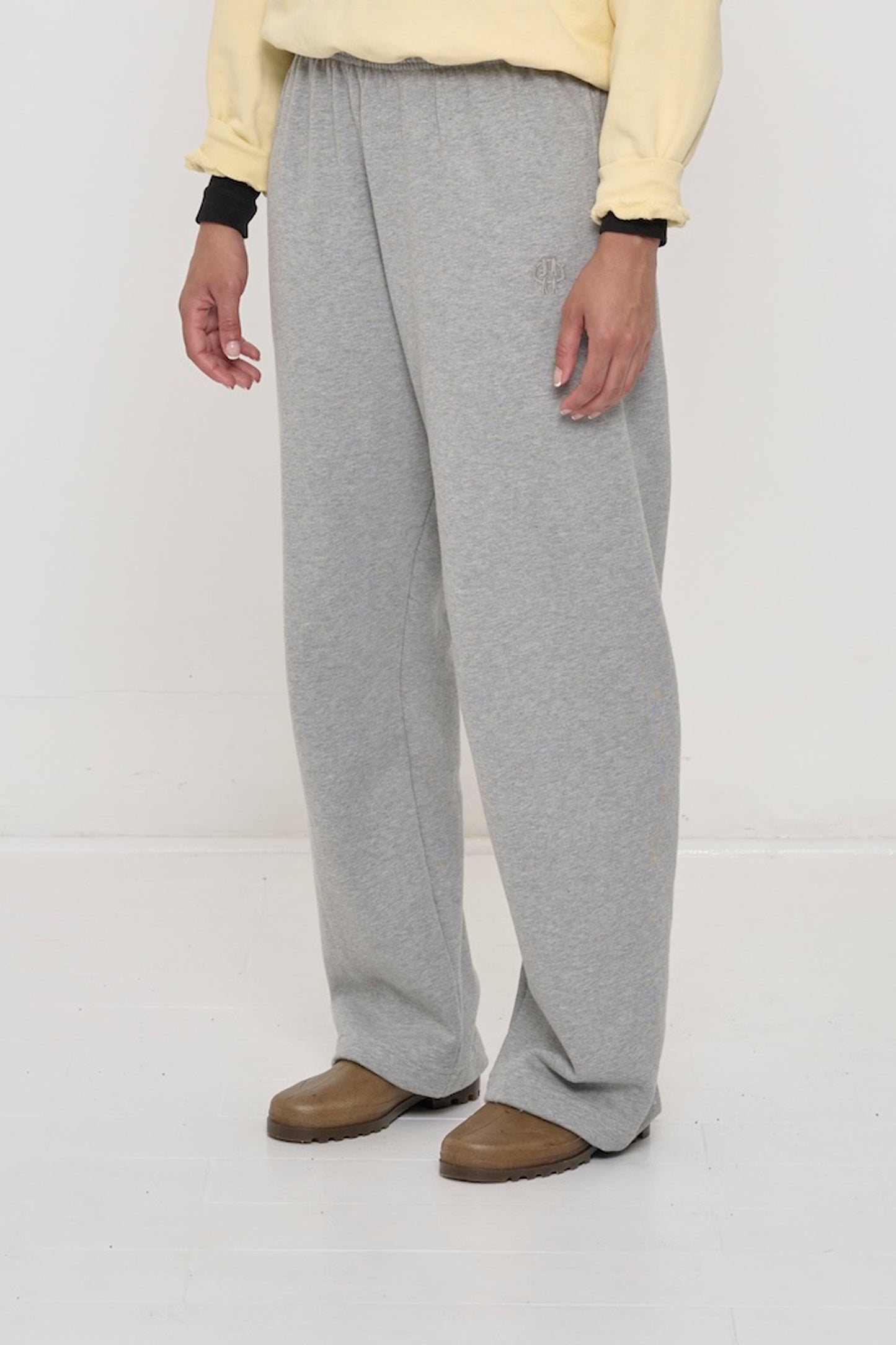 Person turned 45 degrees, in Heather Sweatpants. Shows inseam and tonal logo embroidery near front side pocket.