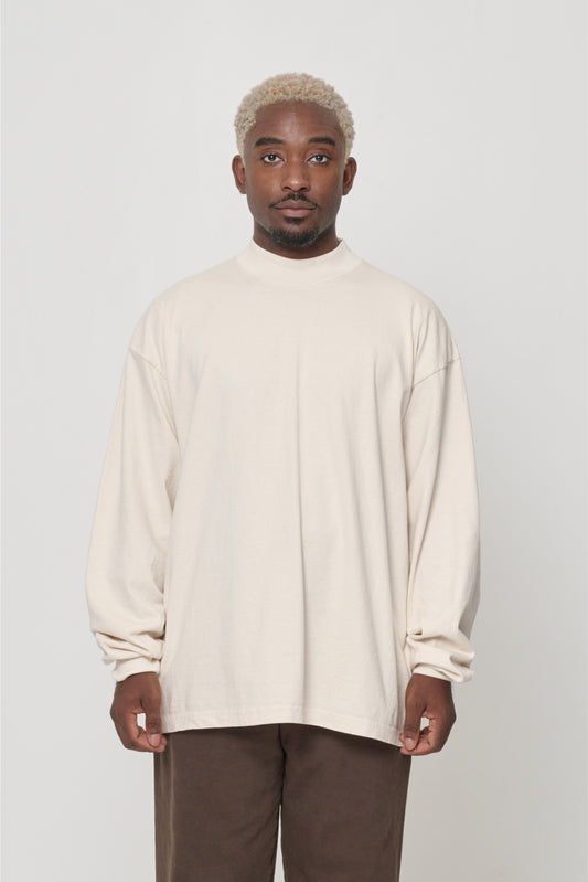 A person wearing a beige long-sleeve t-shirt with a rib knit mock neck collar