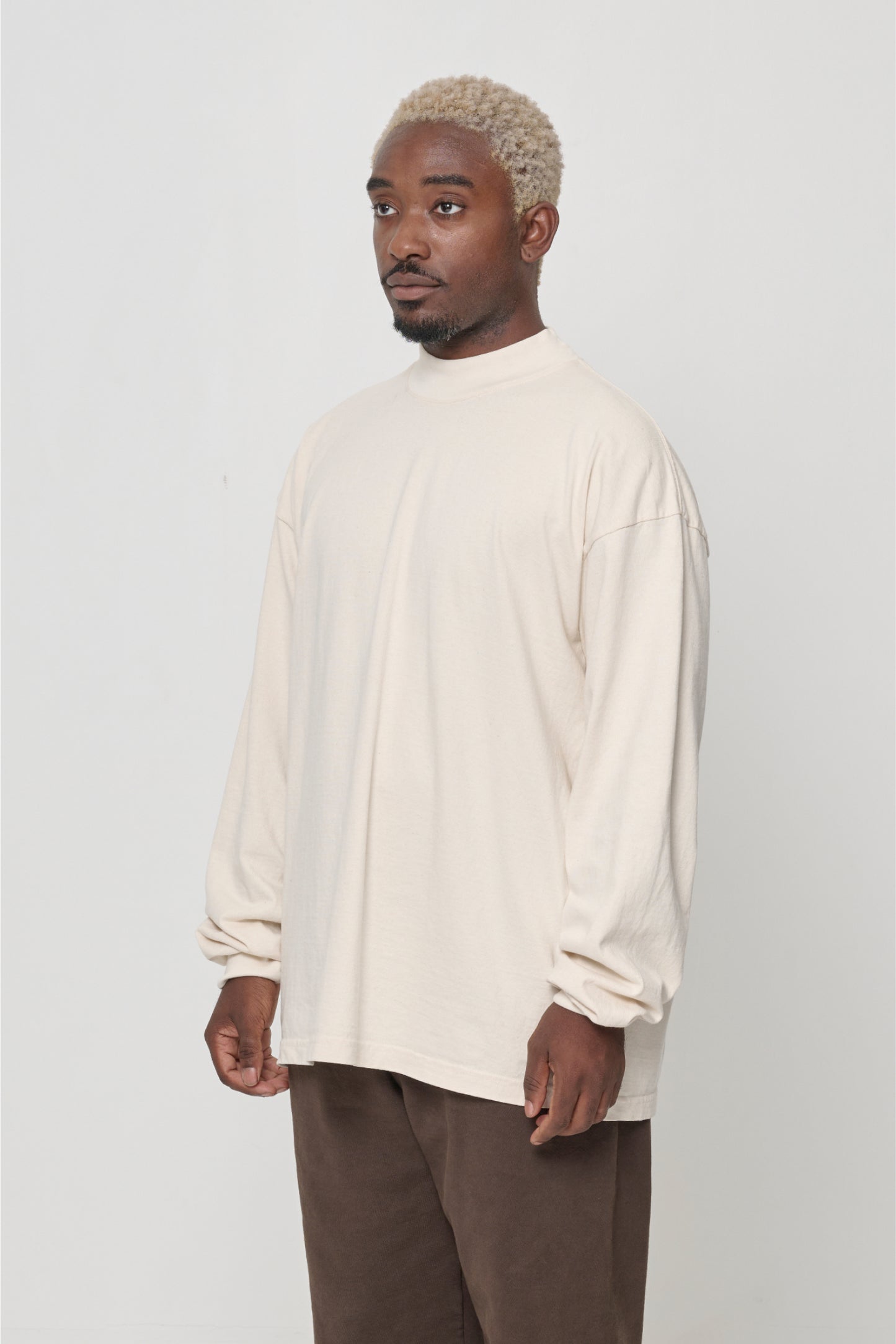 Close up 3/4 front view of person wearing a Scour (pale beige) JAS Mockneck long-sleeve t-shirt showing relaxed fit.