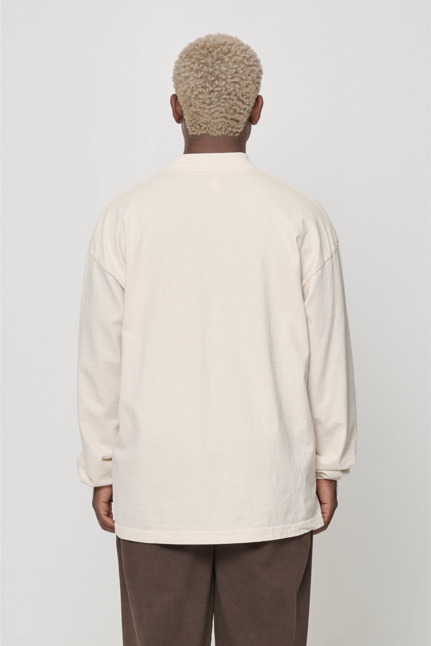 Close up back view of person wearing a Scour (pale beige) JAS Mockneck drop shoulder long sleeves.