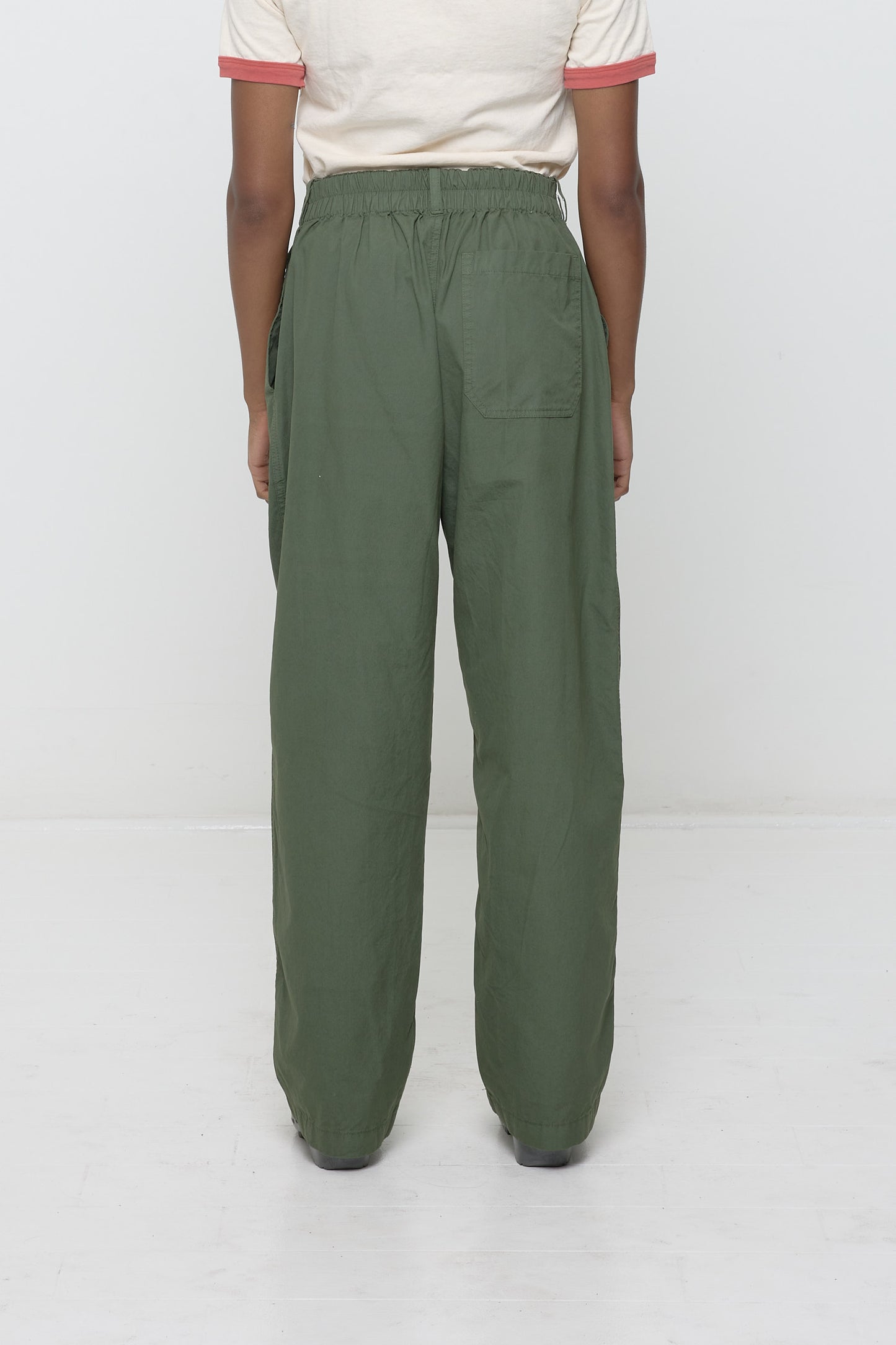 Lower back view of a woman wearing Life Uniform Pants in Pine. Shows elasticized back waistband and right back pocket.