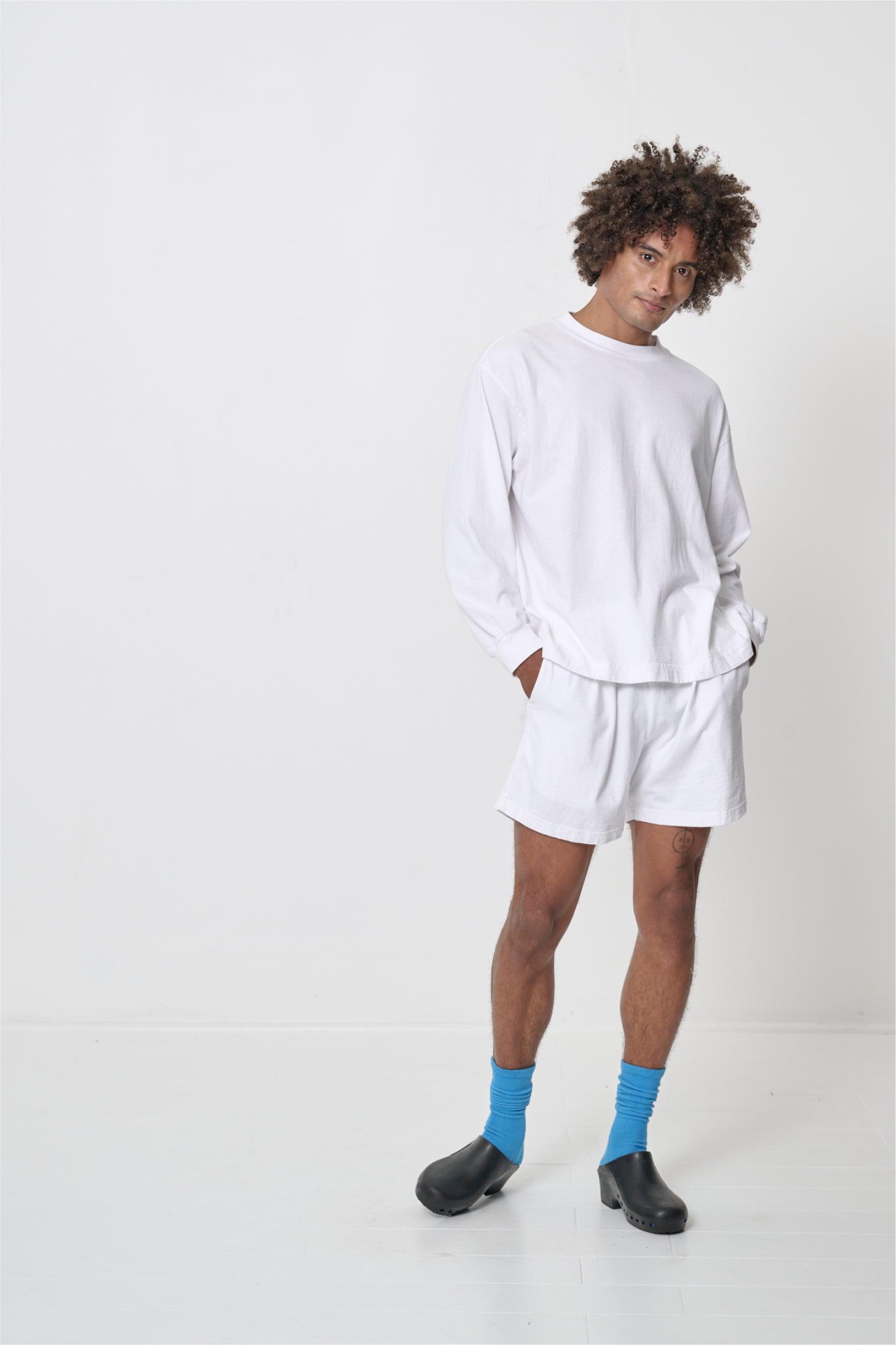 Hands in his shorts pockets, showing soft relaxed texture of shirt.