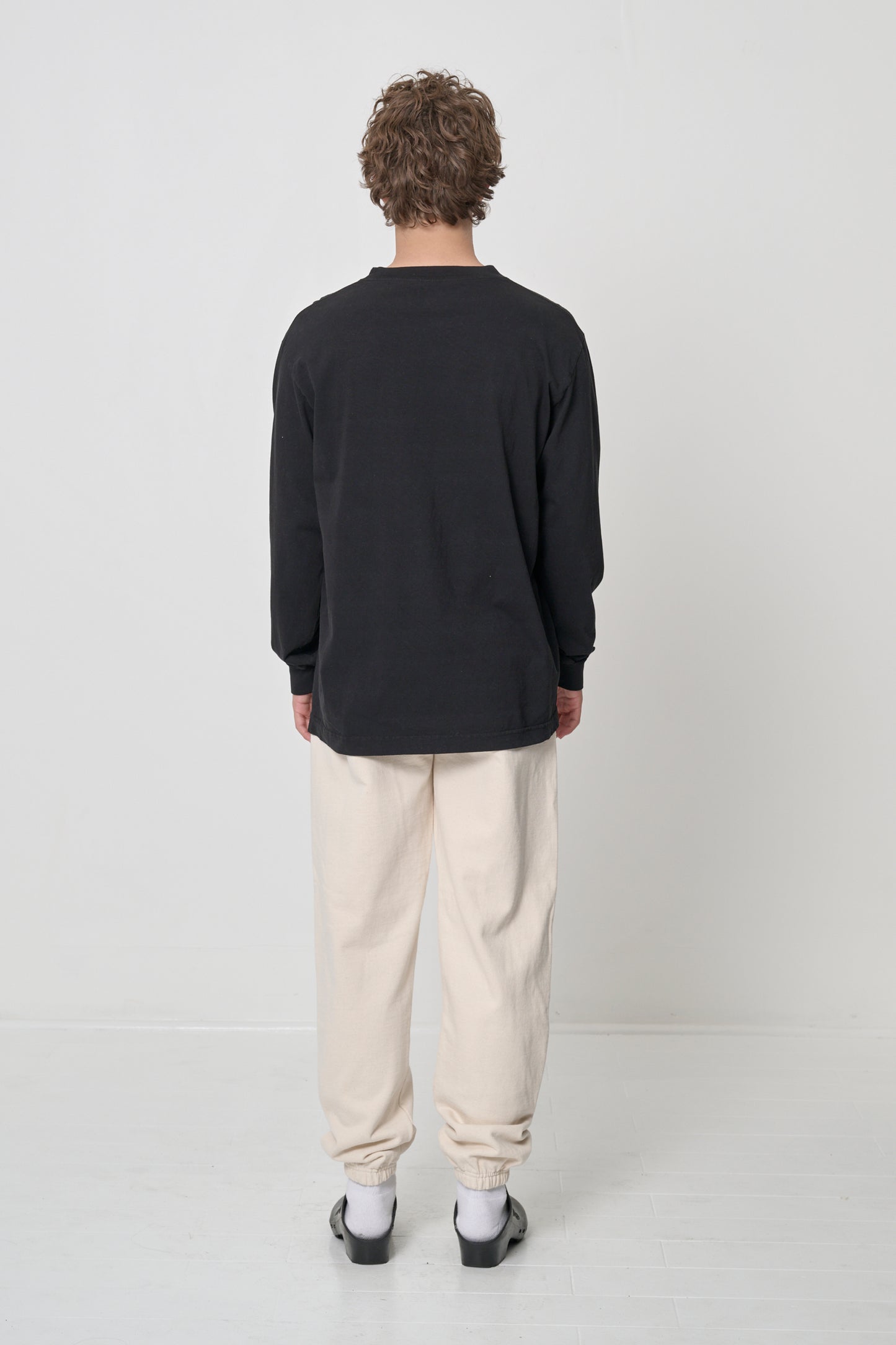 Full length back view of a person wearing a Black Long Sleeve Trash Tee, with Scour Trash Sweatpants.