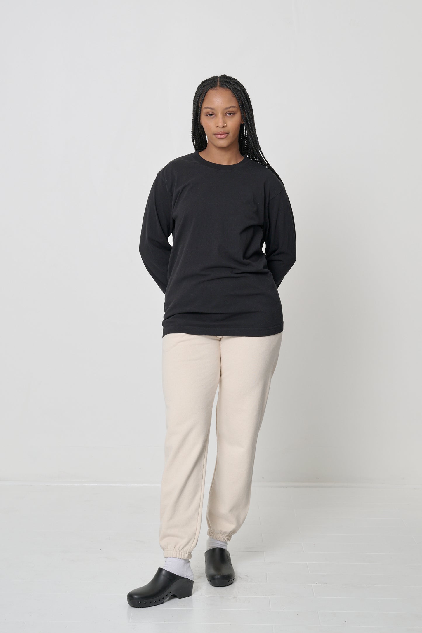 Full length of a woman wearing a Black Long Sleeve Trash Tee, with hands behind her back.
