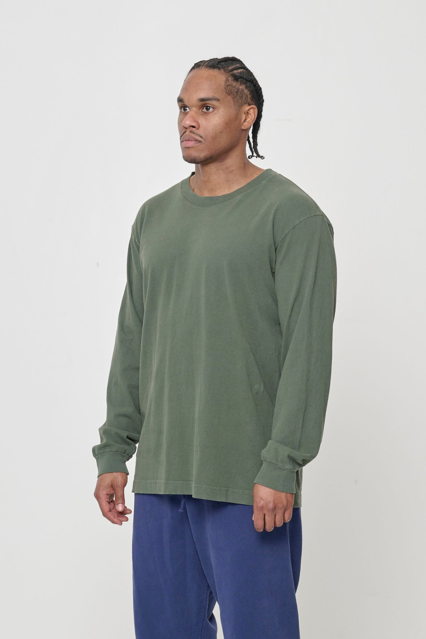 A person turned 45-degrees from the front, in a Pine Long Sleeve Boxier Trash Tee, shows the relaxed sleeves and rib cuff.
