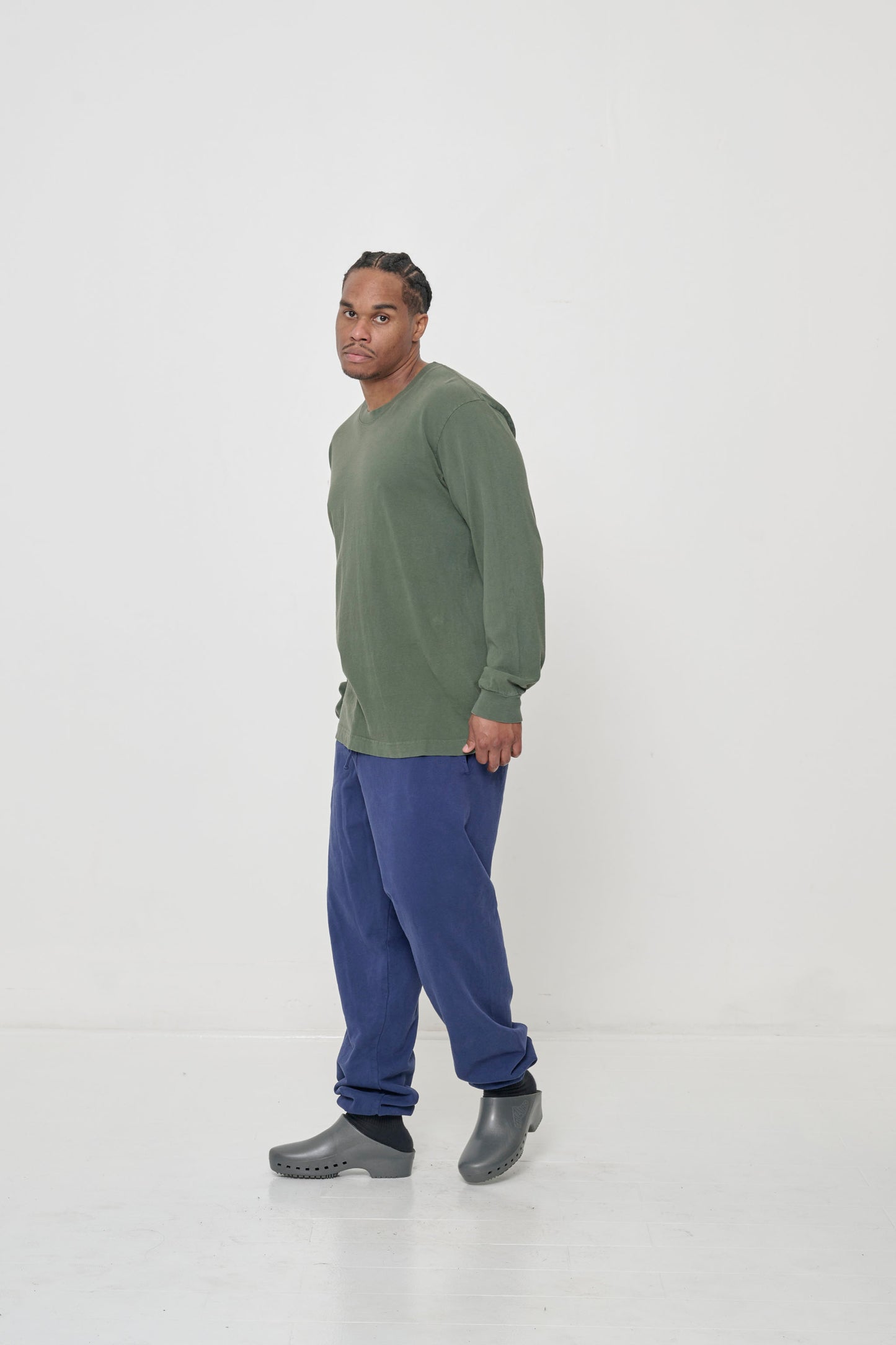 Full length side view of man wearing a Pine Long Sleeve Trash Tee, showing relaxed drape of shirt's sleeves.